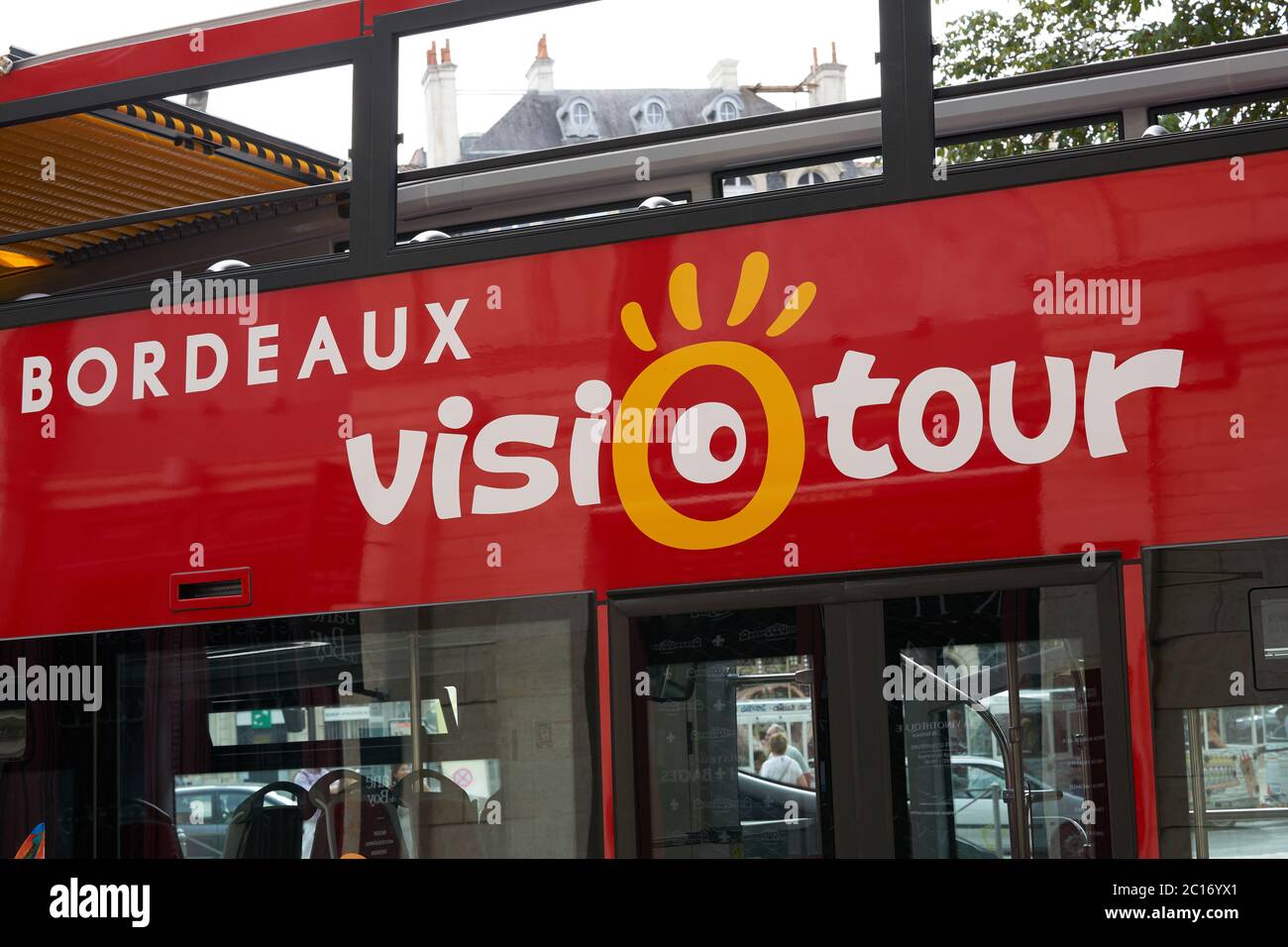 Die Seite eines roten offenen Sightseeing-Busses in Bordeaux, Frankreich, mit einem historischen Haus im Hintergrund Stockfoto