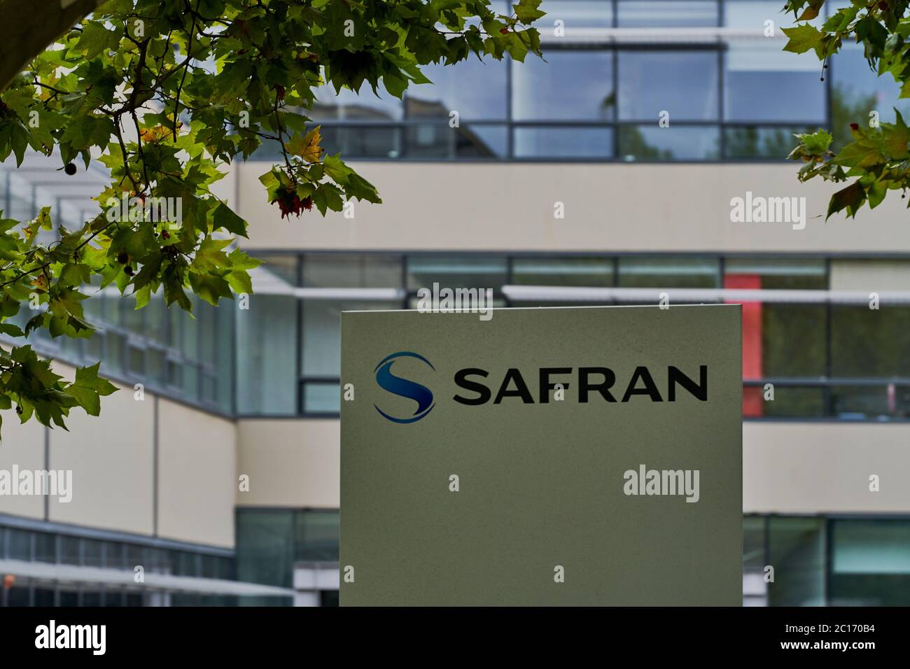 Das Safran-Logo an einem modernen Glasbürogebäude, eingerahmt von Platanenblättern, 12 Quai des Queyries, Bordeaux, Frankreich Stockfoto
