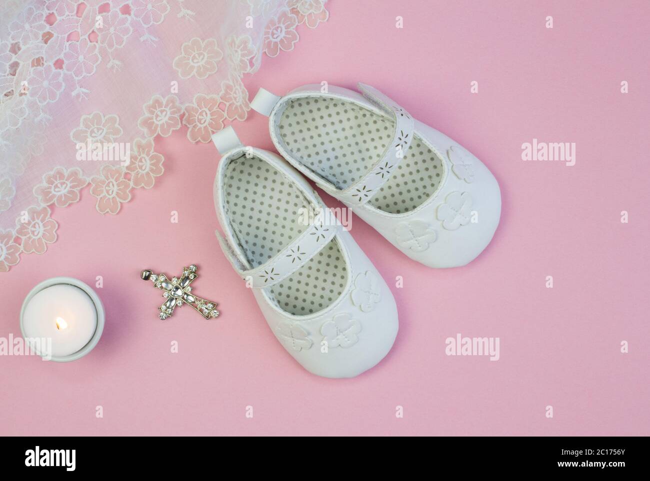 Paar weiße Babyschuhe auf rosa Hintergrund mit Taufe Spitzenkleid und Kerze  Stockfotografie - Alamy