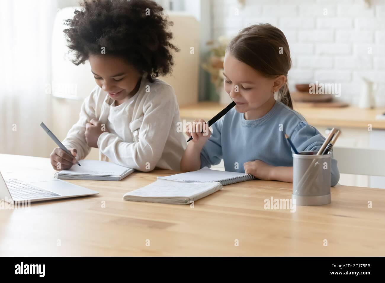 Zwei multi ethnische Schwestern kleine Mädchen machen Hausaufgaben zu Hause Stockfoto