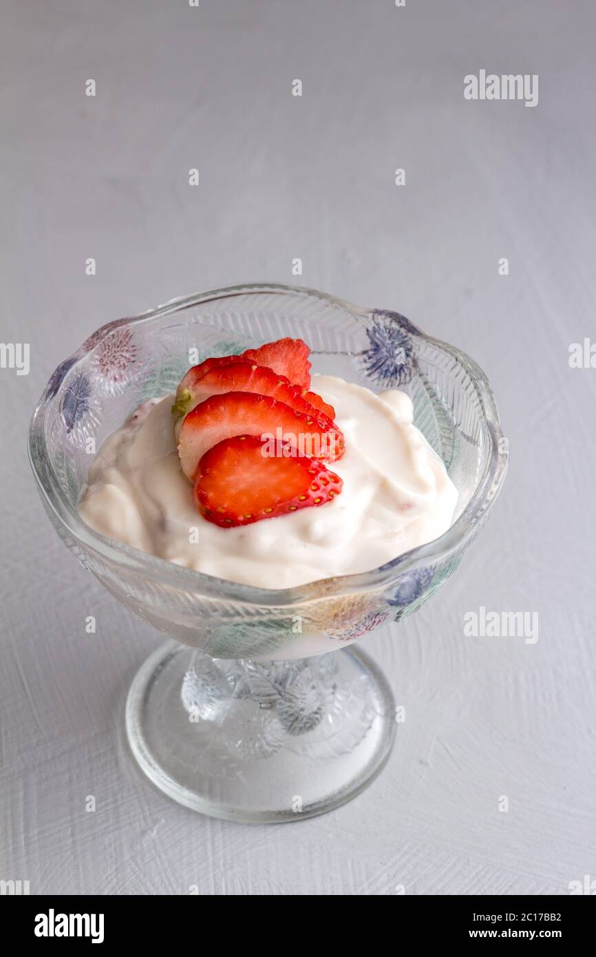 Joghurt in Glasschale mit schneiden Erdbeer Topping auf grauem Hintergrund isoliert Stockfoto