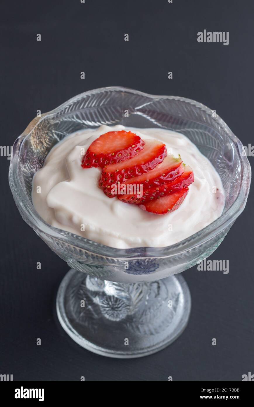 Joghurt in Glasschale mit schneiden Erdbeer Topping auf schwarzem Hintergrund isoliert Stockfoto