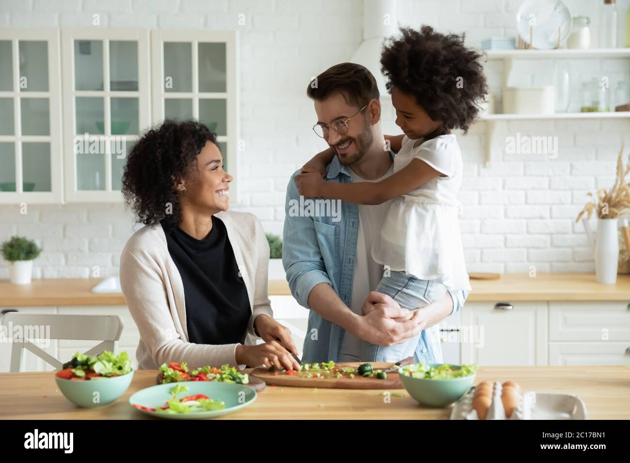 Afrikanische Frau bereitet Abendessen und plaudern mit Tochter und Mann Stockfoto