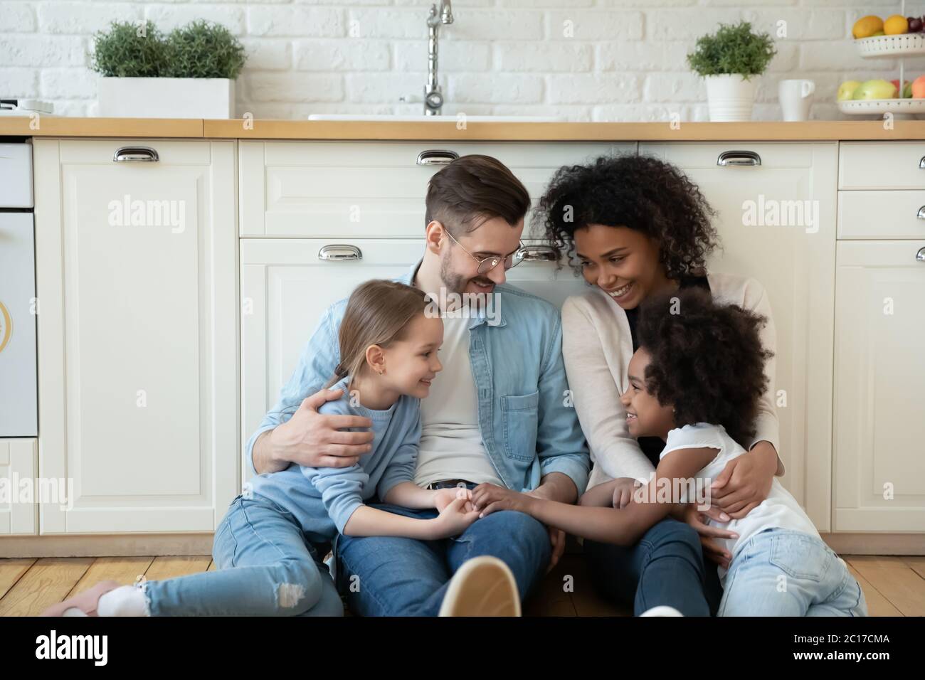 Multinationale Hausbesitzer Familie mit Töchtern Ruhe in modernen Küchenboden Stockfoto