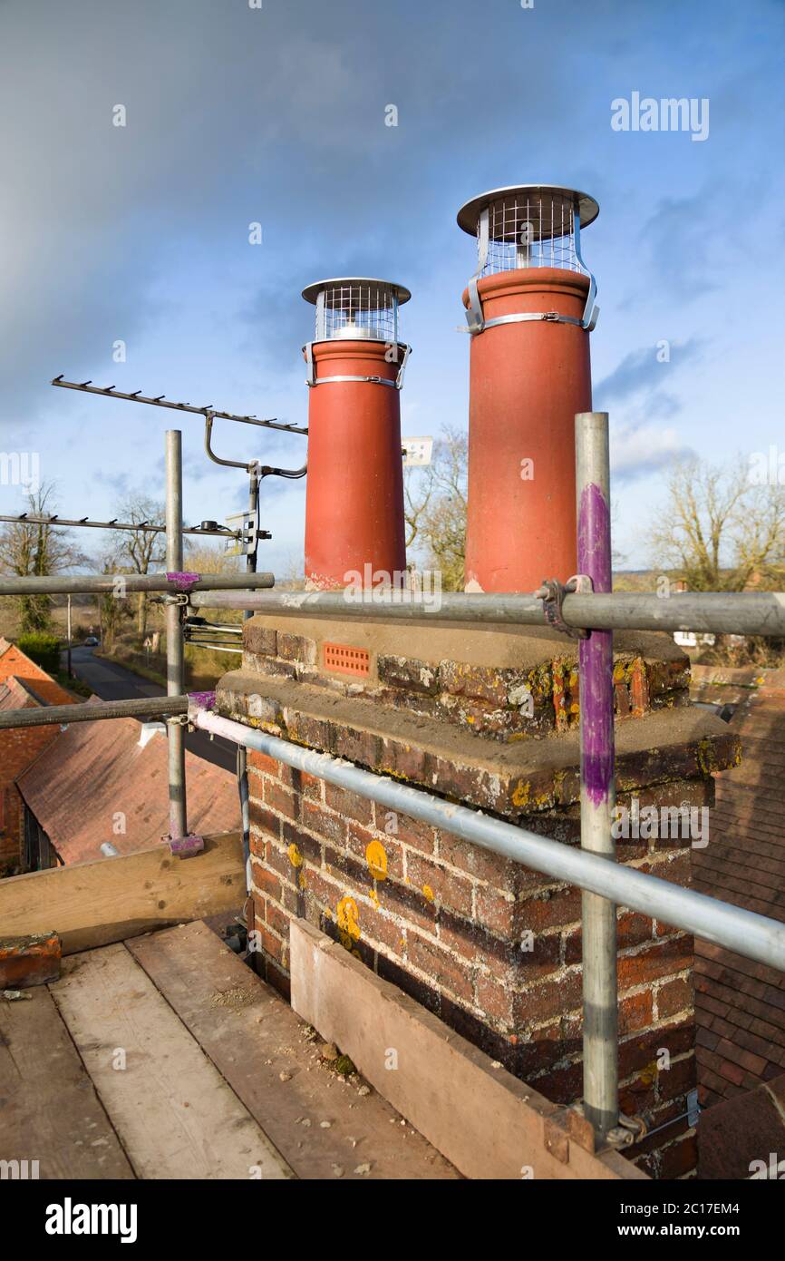 Schornsteintöpfe und Gerüste auf einem Dach. Dachreparaturen während einer Hausrenovierung, Großbritannien Stockfoto