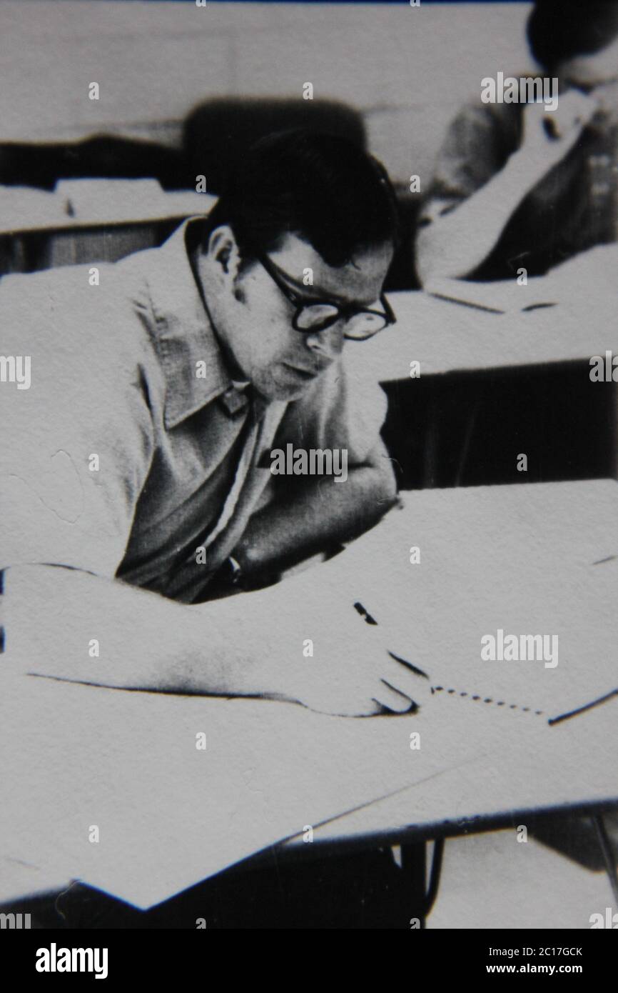 Feine 70er Jahre Vintage schwarz-weiß extreme Fotografie eines professionellen Mannes, der an riesigen Zeichnungen und Papierkram arbeitet. Stockfoto