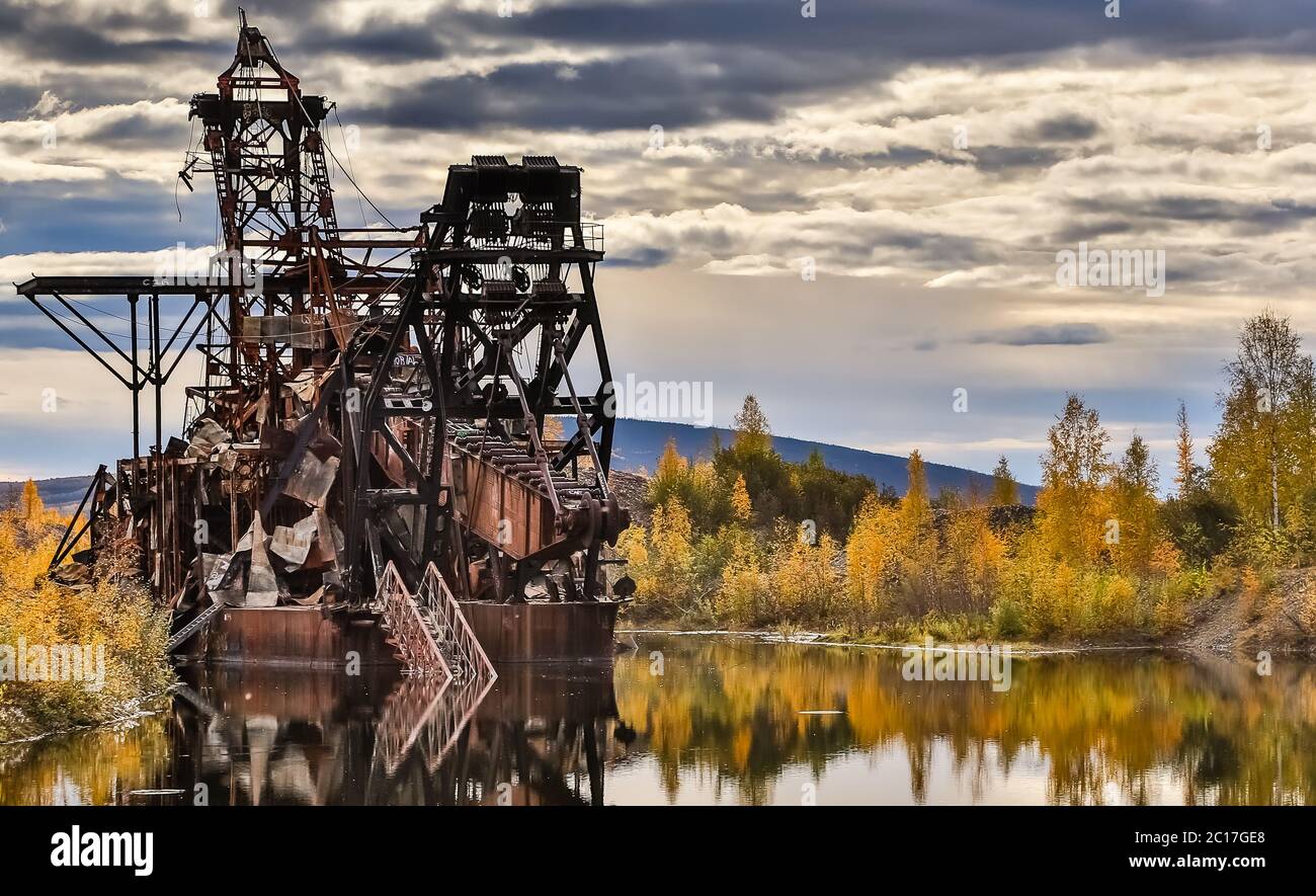 Überreste der historischen Gold Dredge No 3 im Herbst mit Reflexionen auf dem See, Steese Highway, Alaska Stockfoto