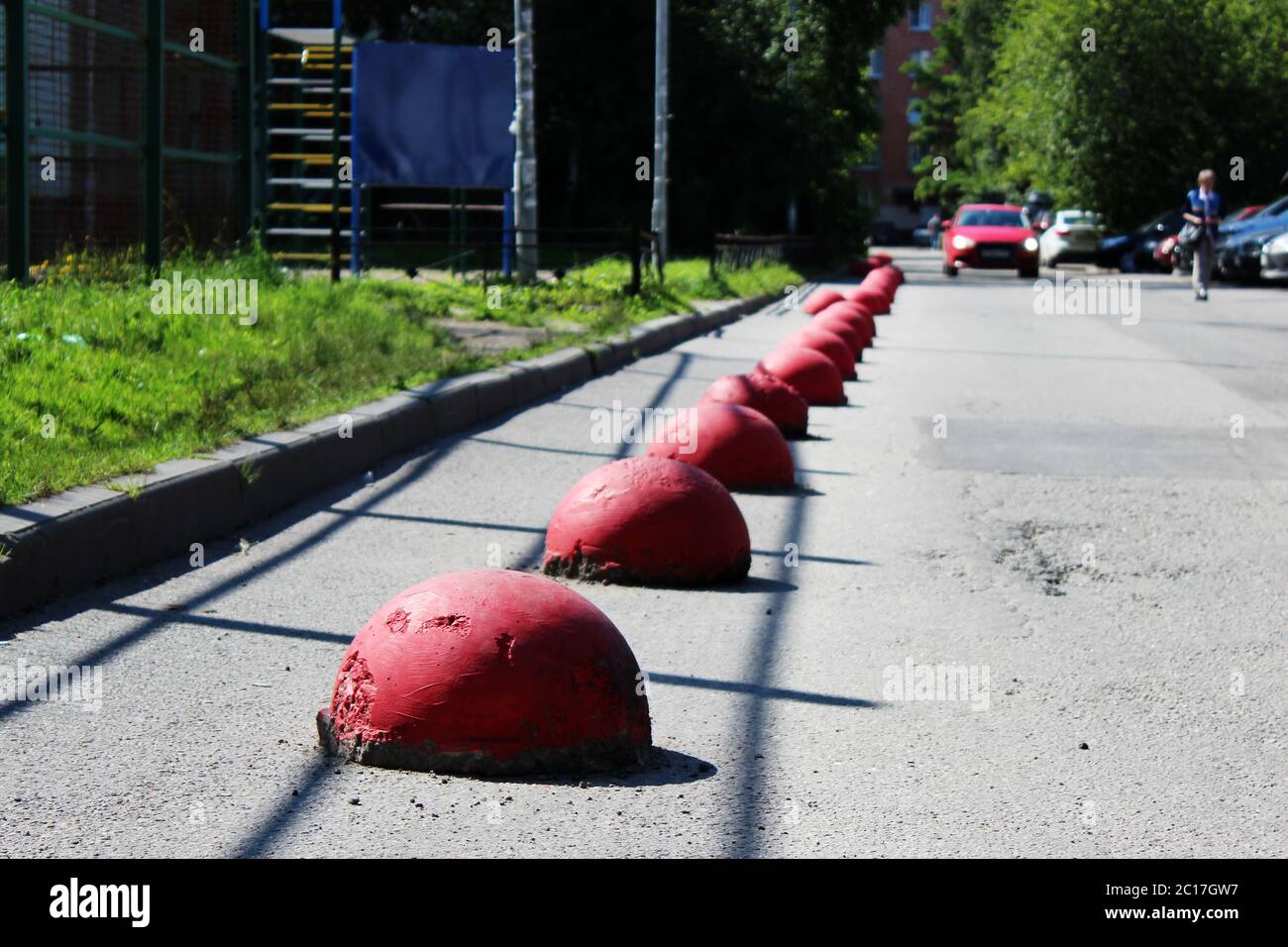 Kugelförmige rote konkrete Sockel neben dem Haus neben der Straße gegen das Eindringen von Fahrzeugen. Stockfoto