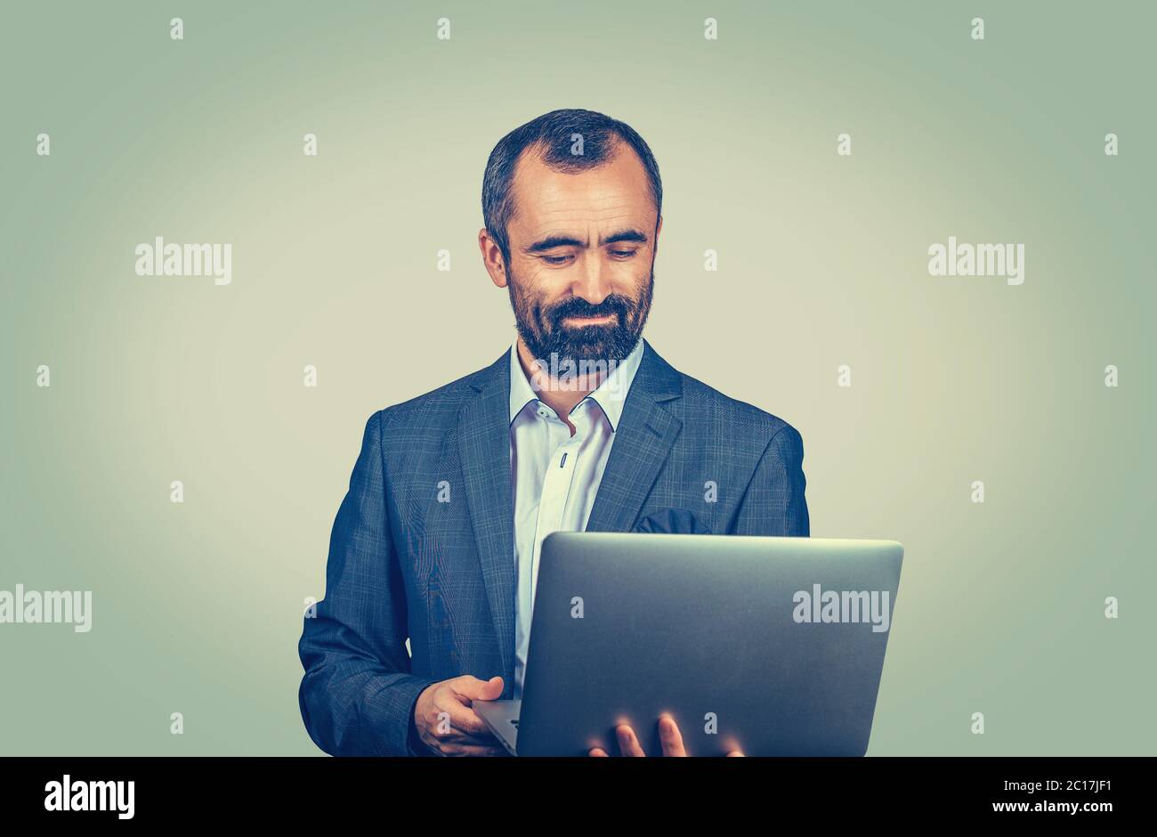 Junge hübsche Reife mittlere Alter Geschäftsmann Verbindung über aufmerksam, die in einem Laptop mit Internetzugang. Mischlinge bärtigen Kerl isoliert auf Grün s Stockfoto