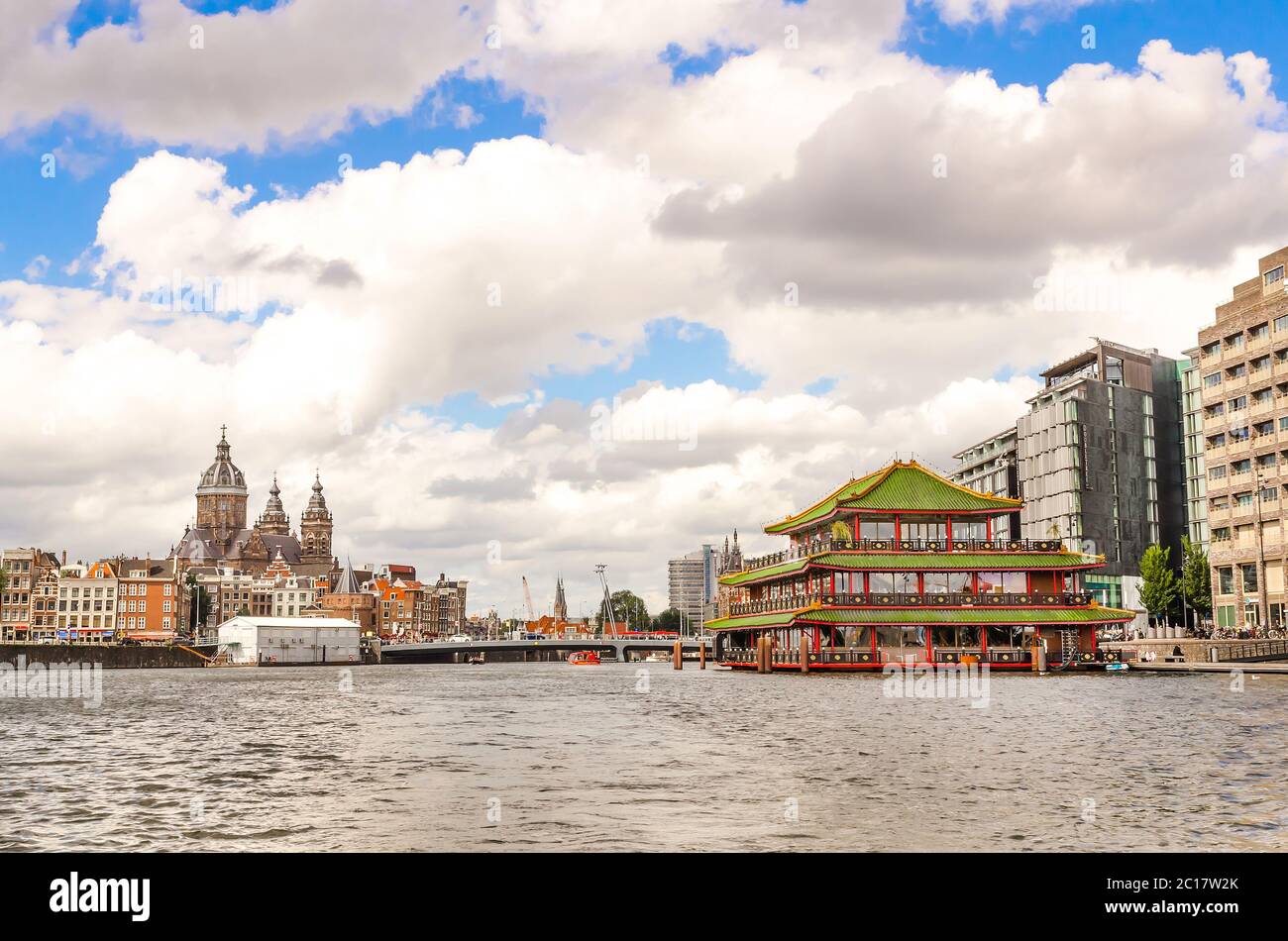 AMSTERDAM, HOLLAND - AUG 31, 2019: Panoramablick auf die Stadt des berühmten schwimmenden chinesischen Restaurants und der historischen Kirche Saint Nicolas in einer wunderschönen Wolke Stockfoto
