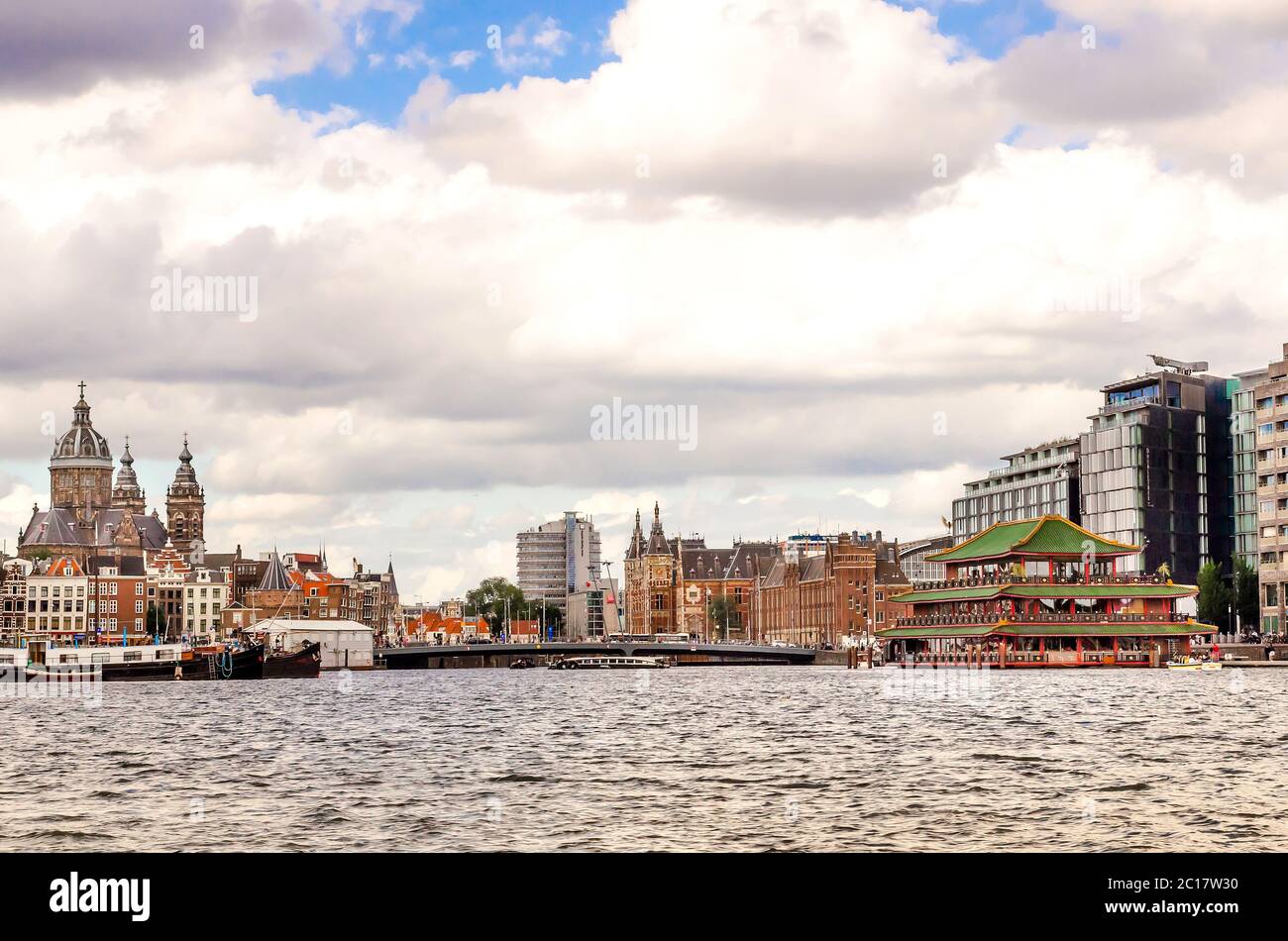 AMSTERDAM, HOLLAND - AUG 31, 2019: Panoramablick auf die Stadt des berühmten schwimmenden chinesischen Restaurants und der historischen Kirche Saint Nicolas in einer wunderschönen Wolke Stockfoto
