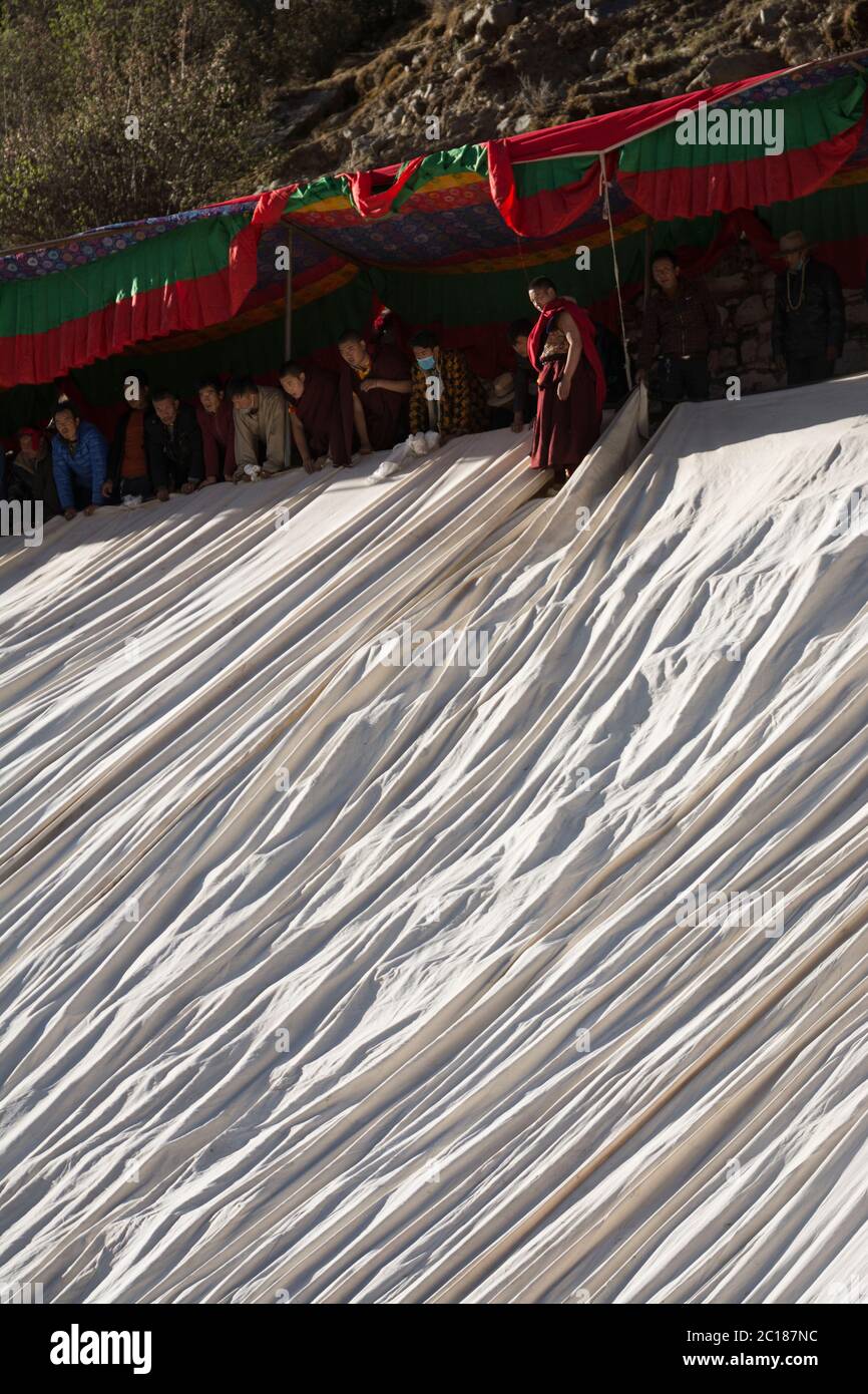 Ein Mönch überwacht die Einstellung von riesigen Stoffbahnen, über denen das riesige Bild eines Buddha, ein Thangka, ausgestellt wird, Tsurphu Kloster, Tibet Stockfoto