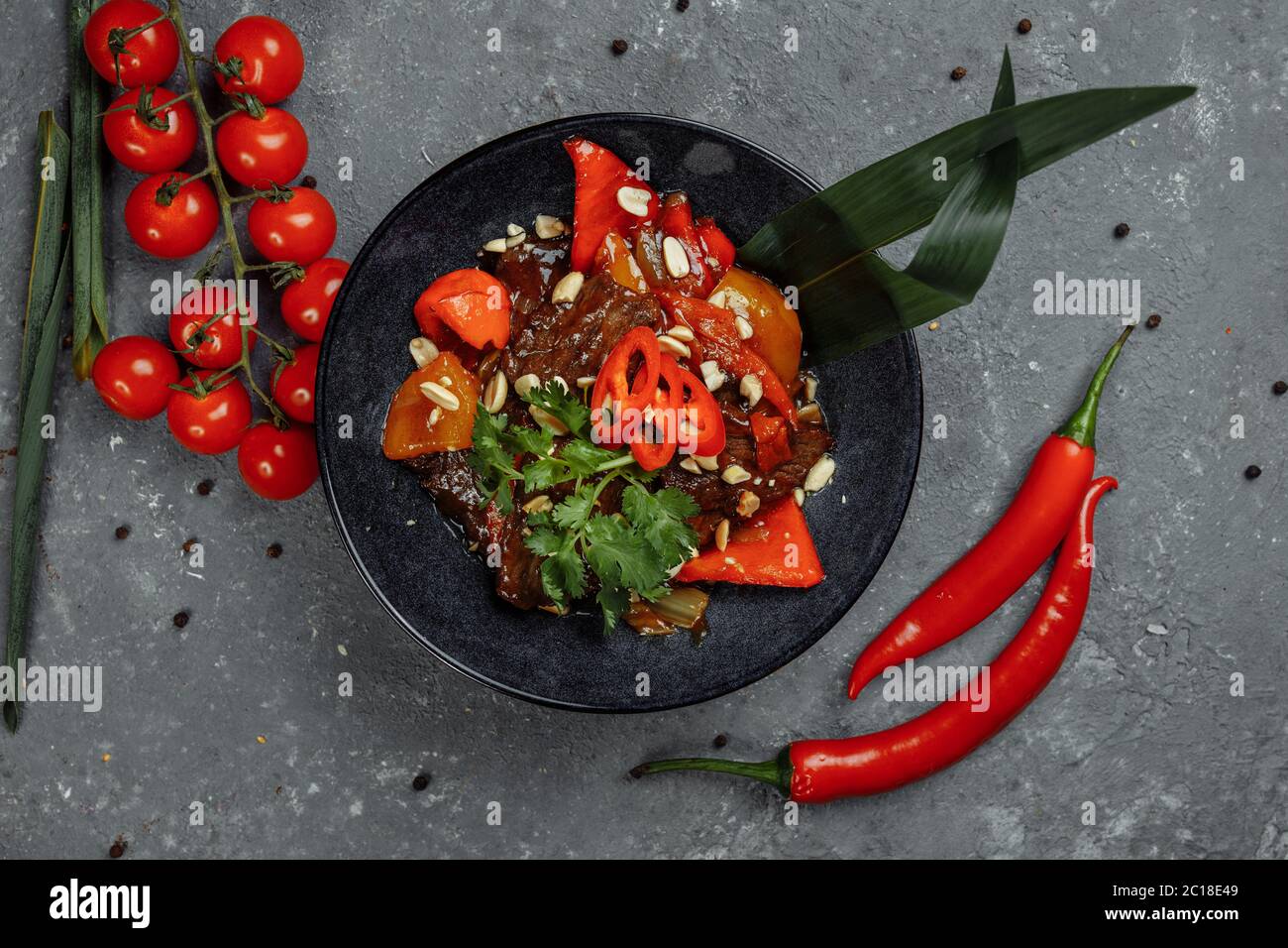 Rinderwak. Traditionelle chinesische mongolische Rindfleisch rühren braten in chinesischen Gusseisen Wok mit Kochstäbchen, Stein Schiefer Hintergrund. Draufsicht, Kopierbereich Stockfoto