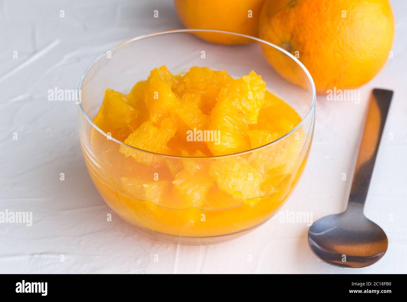Frische Orangenfrucht Scheiben mit Saft in Glas Dessertschale auf weiß rustikalen Oberfläche Hintergrund und tw Stockfoto