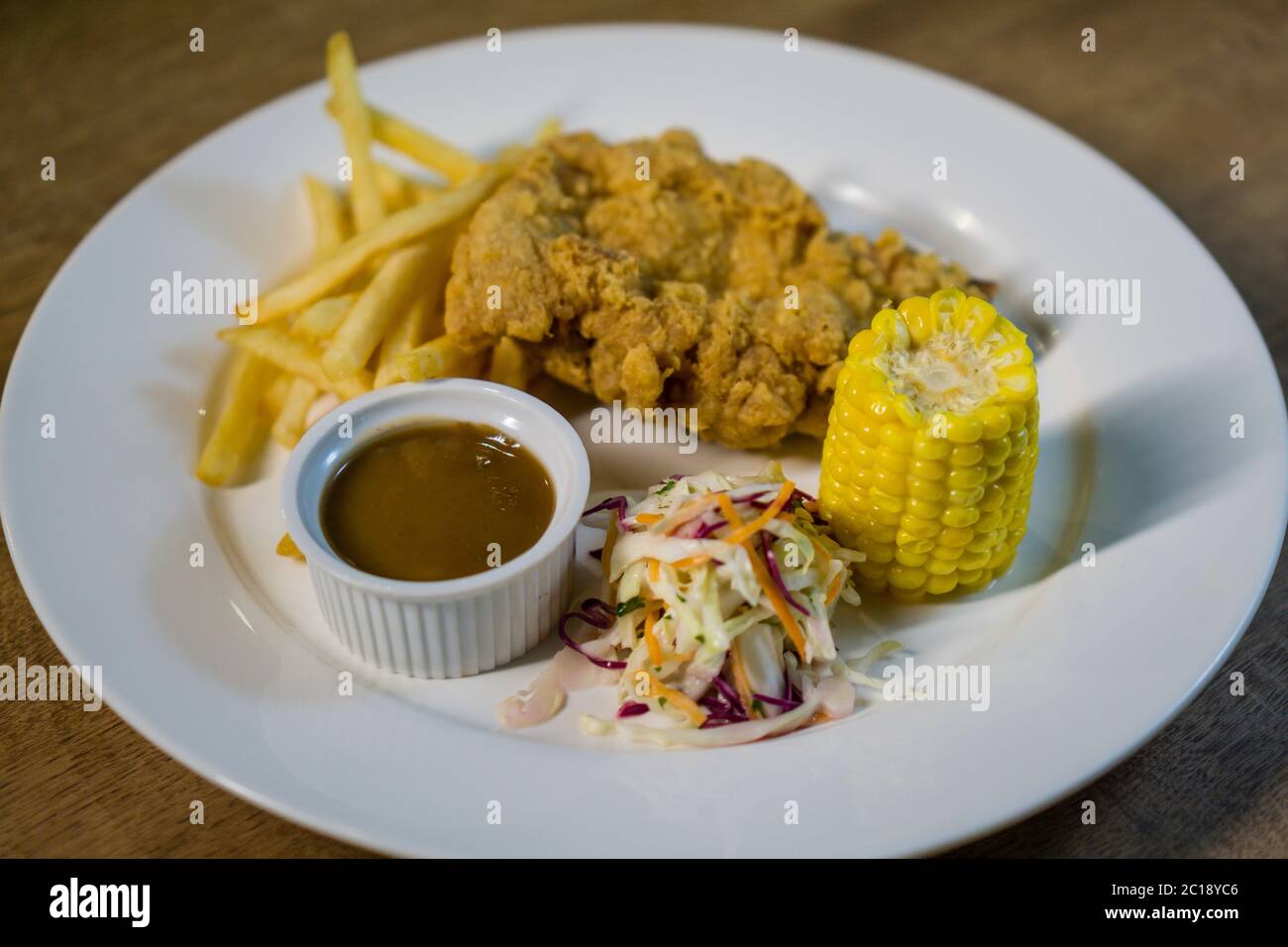 Frittiertes Hühnerfleisch mit Pommes Frites, Mais, Coleslaw dan Pilzsauce. Stockfoto