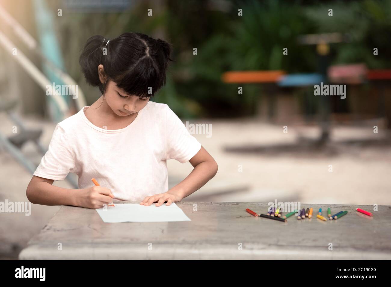 Asiatische Mädchen Kind sitzen und malen auf dem Spielplatz. Stockfoto