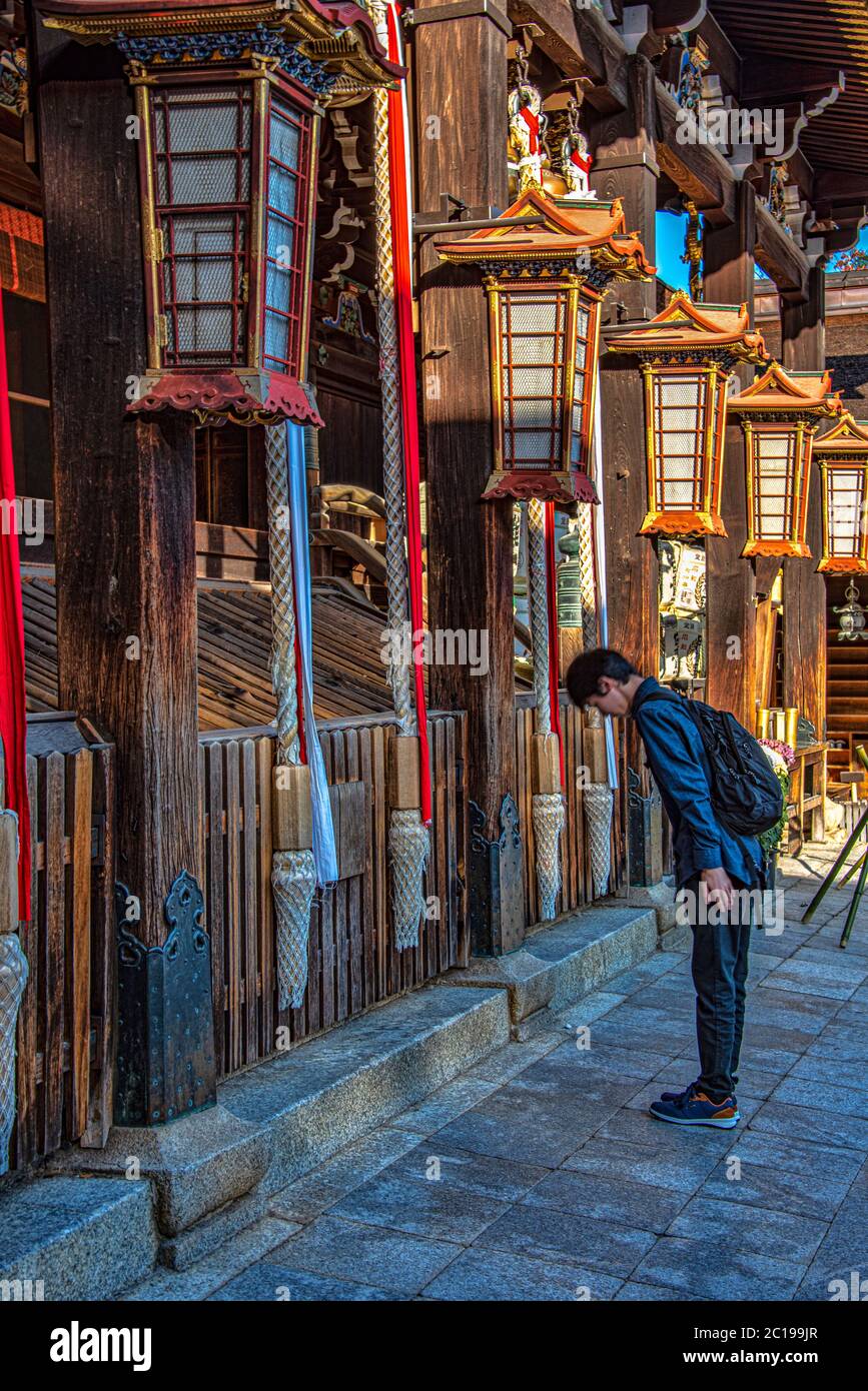 Junger Mann, der im Kitano Tenmangu shinto-Schrein, Kyoto, Japan betet Stockfoto