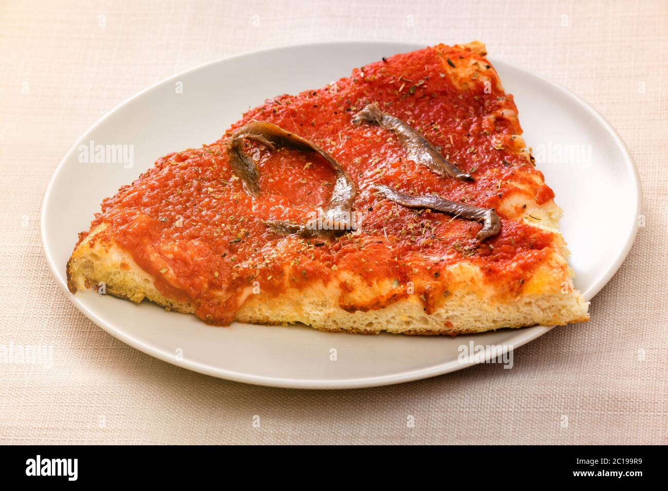 Eine Scheibe Marinara Pizza mit Sardellenbestich auf Tomatenmark in der Nähe serviert auf einem generischen weißen Teller Stockfoto