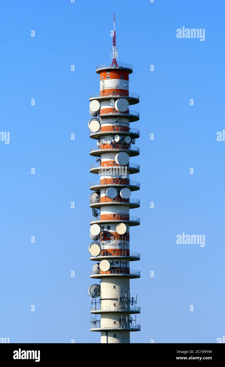 Erhöhte Telekommunikations-Repeater-Turm mit Geschirr, die Kommunikation nach Linie des Standorts zwischen zwei Stationen gegen einen blauen Himmel Stockfoto