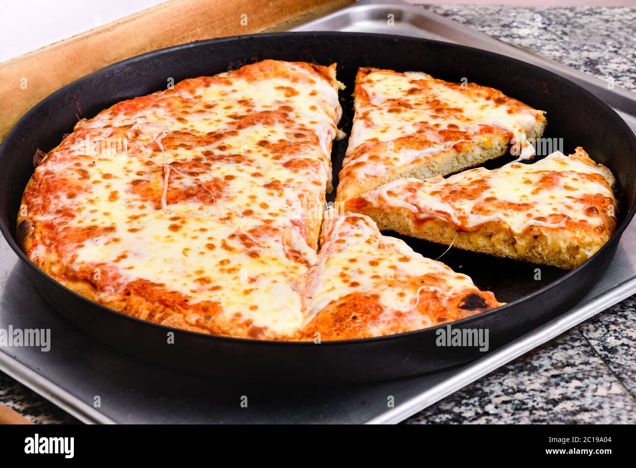 Große frisch zubereitete italienische margherita Pizza in einem Backblech auf einer Küchentheke in Nahaufnahme hohen Winkel geschnitten Stockfoto