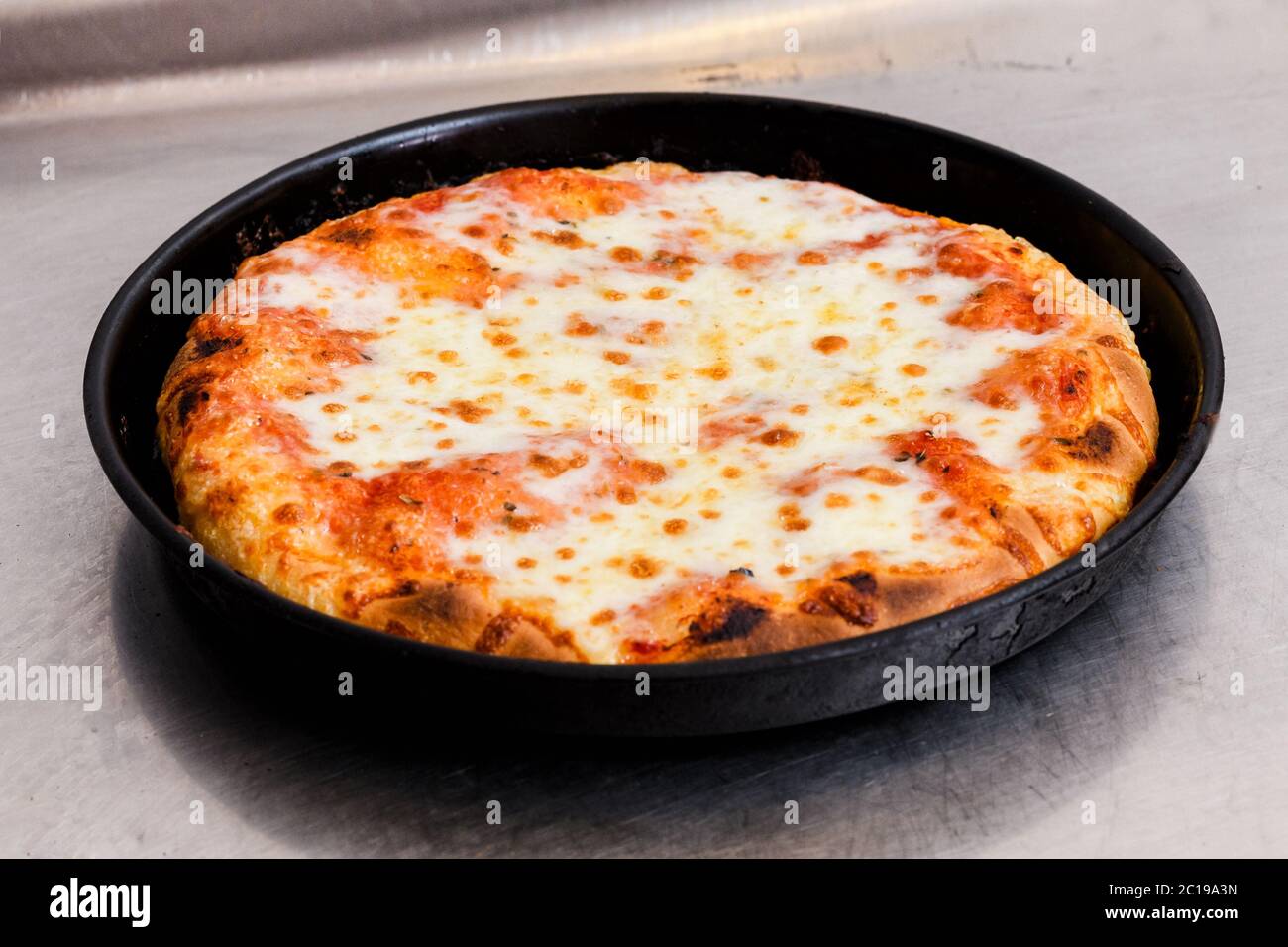 Frisch gebackene oder gegrillte italienische Margherita Pizza in einem runden Backblech auf einer Küchentheke in einer Pizzeria Stockfoto