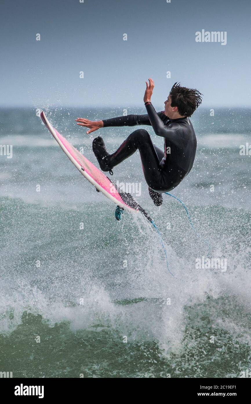 Spektakuläre Action, wenn ein Surfer von einer Welle bei Fistral in Newquay in Cornwall in die Luft kommt. Stockfoto