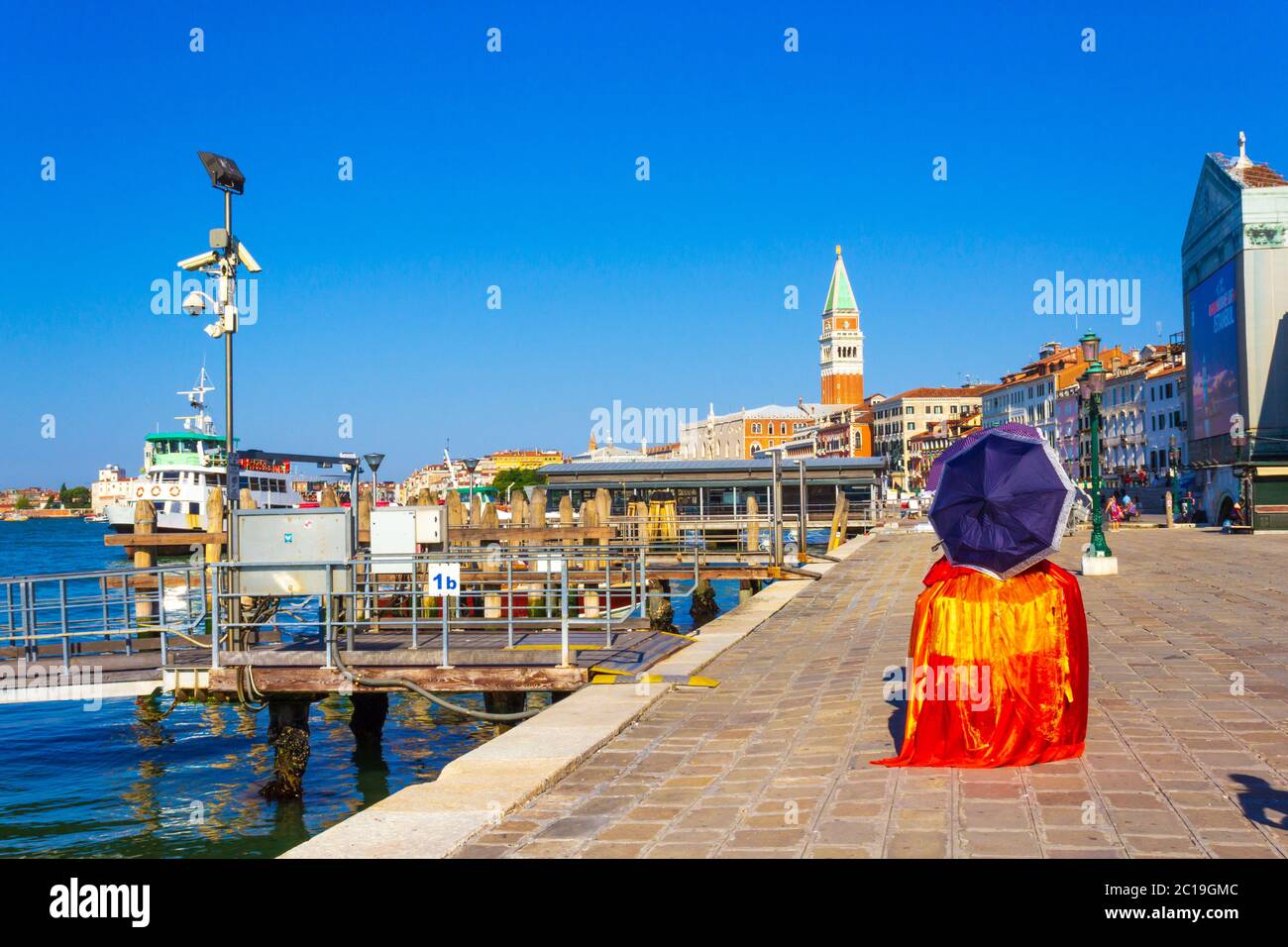 Hölzerne Piers, Karneval verkleidete Frau an der dennoch ruhigen Küstenstraße ohne Massen von Touristen und die schönen historischen Gebäude am Meer in Venedig Stockfoto