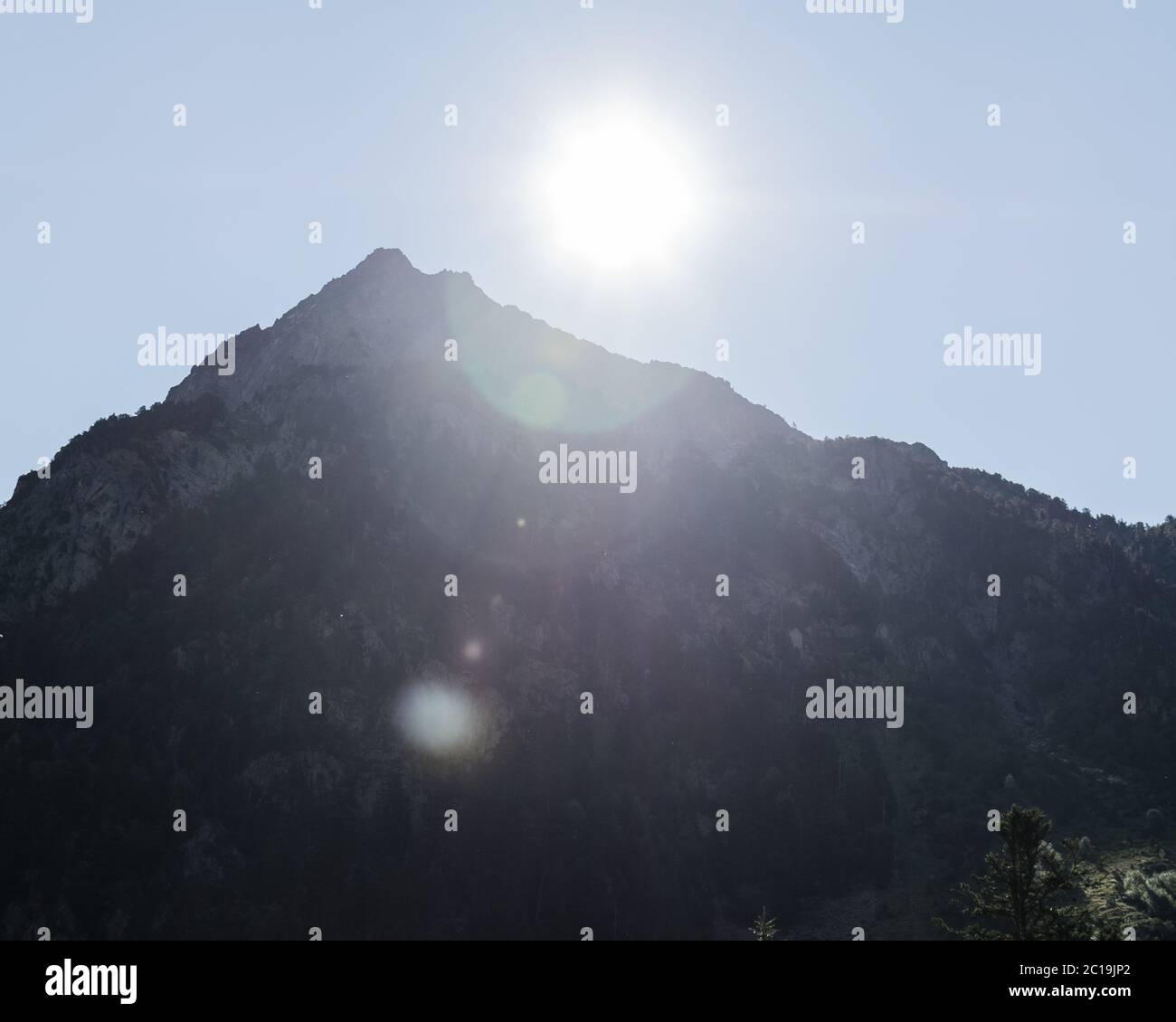 Blick auf den Gipfel eines hinterleuchteten Berges mit einem Lichtreflexe. Stockfoto