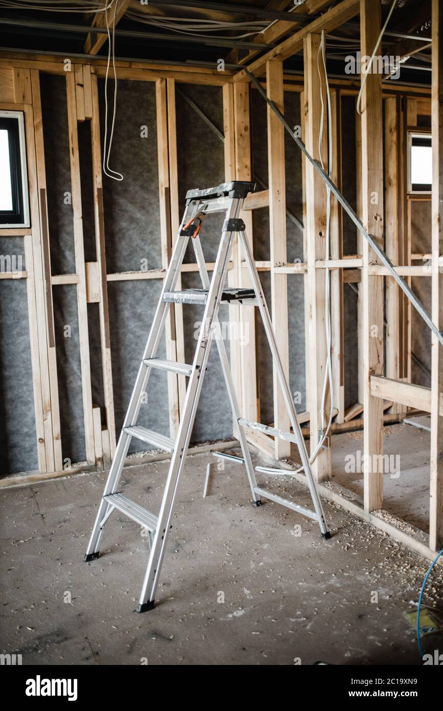 Ein Bauket eines Hauses, das mit freiliegenden Drähten und Holzbalken und einer Leiter gebaut wird Stockfoto