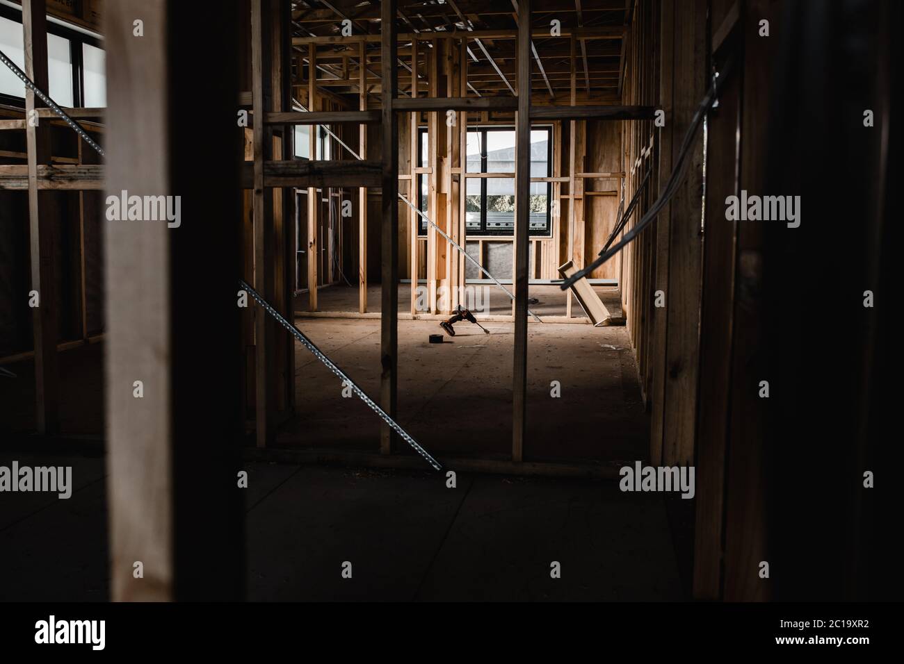 Eine Konstruktion eines Hauses, das mit freiliegenden Drähten und Holzbalken gebaut wird, Licht, das auf die Werkzeuge einleuchtet Stockfoto