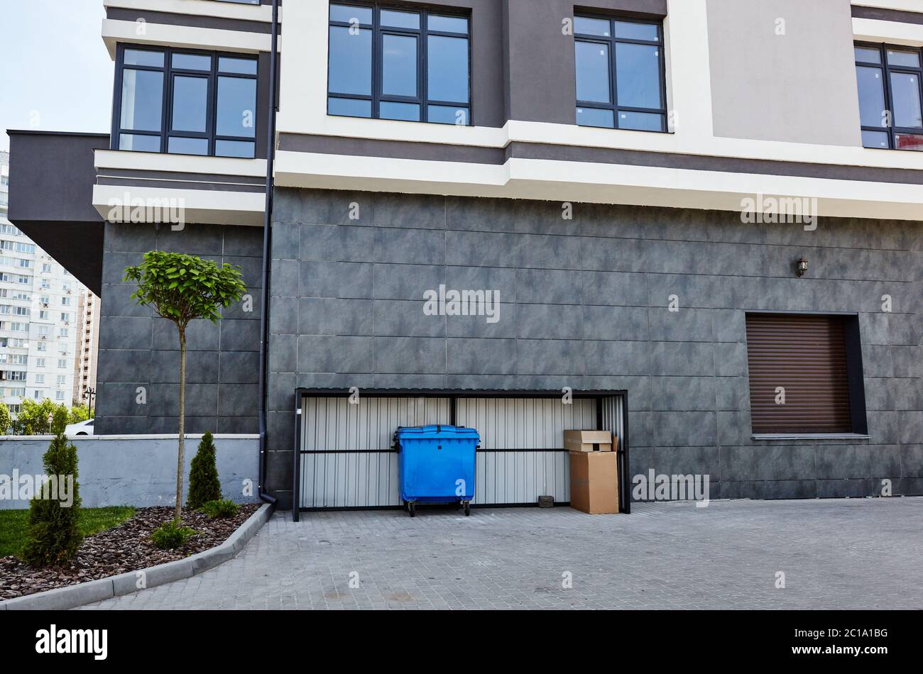 Fassade eines modernen europäischen Apartmentgebäudes. Blauer Container, Mülltonne.Sanitary Standards.Abstract Architektur, Fragment der modernen städtischen Geometrie Stockfoto