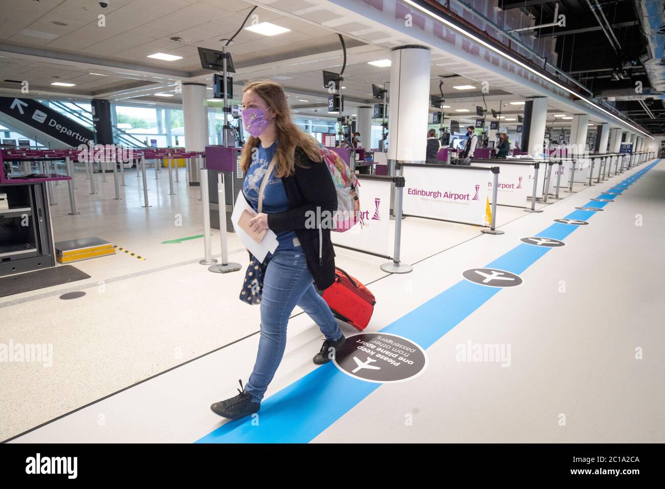 Passagiere folgen dem One-Way-System durch den Flughafen Edinburgh, eine der sozialen Entfernungsmaßnahmen, die den Kontakt mit Flughafenpersonal und Reisenden einschränken. Stockfoto