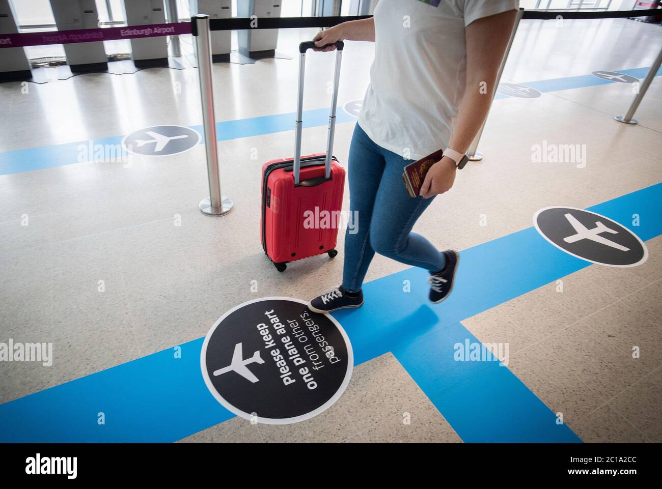 Passagiere folgen dem One-Way-System durch den Flughafen Edinburgh, eine der sozialen Entfernungsmaßnahmen, die den Kontakt mit Flughafenpersonal und Reisenden einschränken. Stockfoto