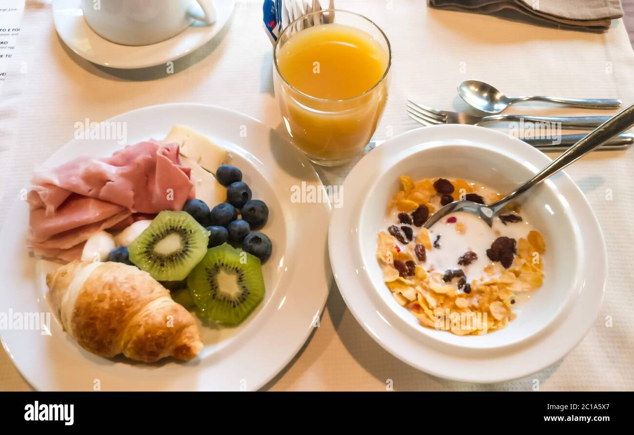 Typisch italienisches Frühstück mit Schinken, frischen Käsebällchen, Saft und Müsli Stockfoto