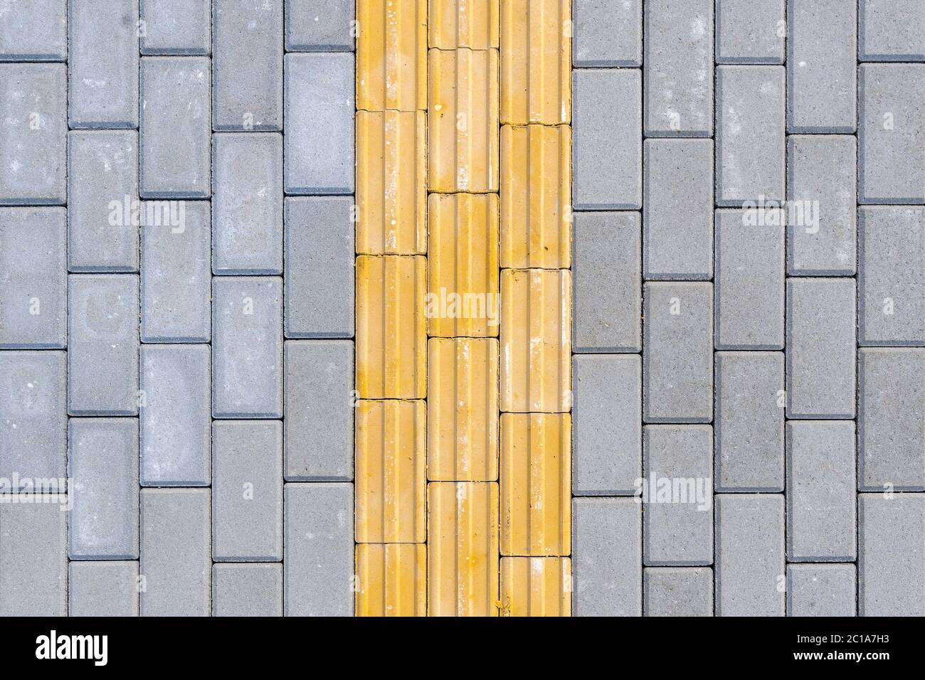 Hellgelbe taktile Pflastersteine für Sehbehinderte auf dem Bürgersteig. Stockfoto