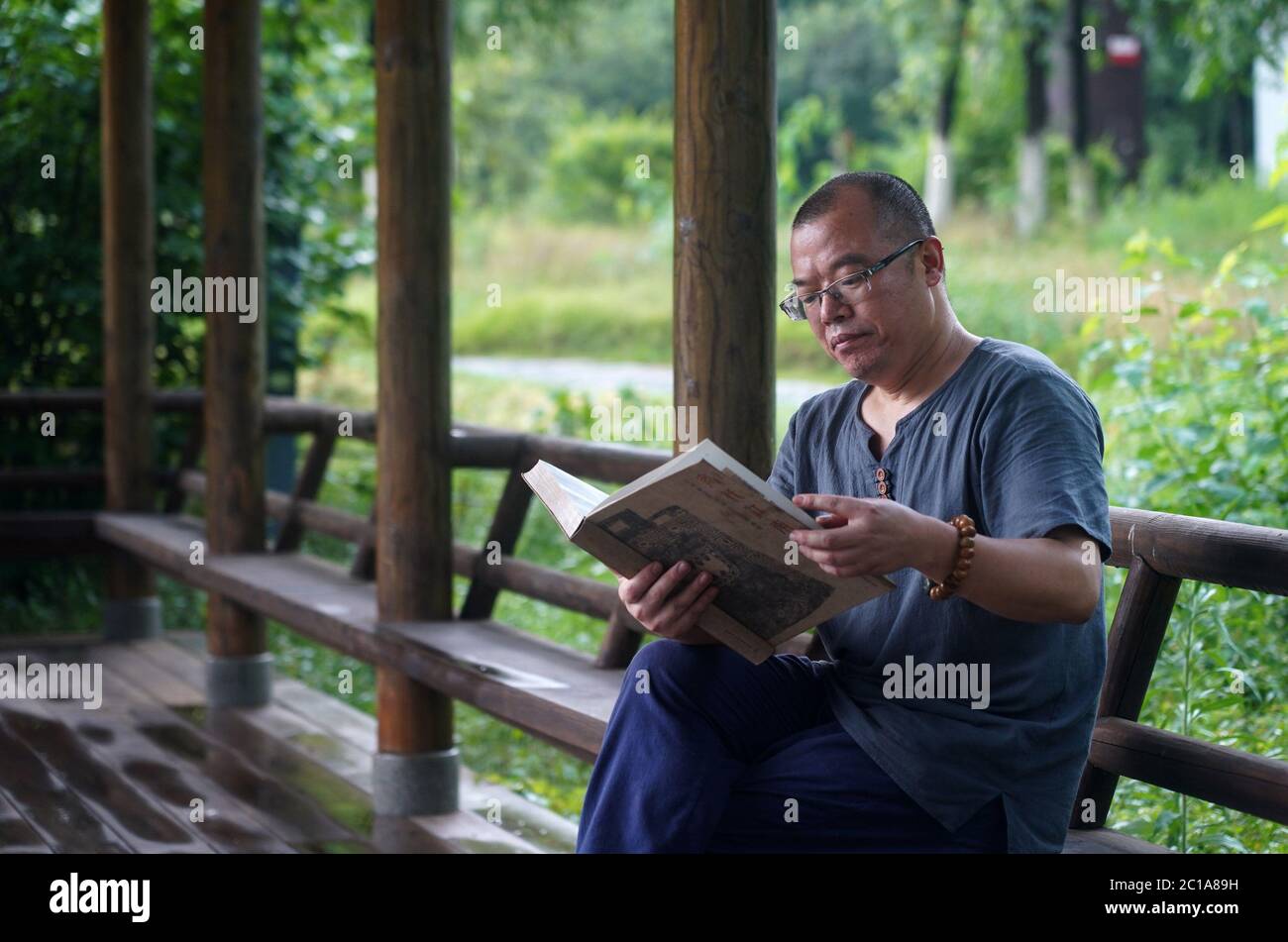 (200615) -- NANCHANG, 15. Juni 2020 (Xinhua) -- der Handwerker Wu Yingshan liest ein Buch in der Nähe seines Ateliers im Bezirk Ji'an, ostchinesische Provinz Jiangxi, 15. Juni 2020. Es gibt keine zwei identischen Blattbecher, genauso wie es keine zwei identischen Blätter auf der Welt gibt. Die Herstellung eines Blattschals, ein traditionelles Handwerk endemisch in der heutigen Ji'an Grafschaft, ist etwas Besonderes - der Handwerker muss ein Blatt in das Porzellan zu integrieren, an dem gearbeitet wird. Wu Yingshan, ein Erbe der Blatt-Tasse Herstellung Techniken, begann zu studieren auf Porzellan im Jahr 2003. Mit der Entwicklung der Massenproduktion, die traditionellen Wege zu machen Stockfoto