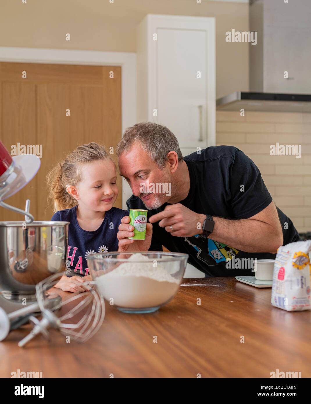 Papa und Tochter machen frischen Pizzateig in Küchenarmatur. Corona Lockdown Kochen. Pizza mit Papa beim Lockdown machen. Stockfoto