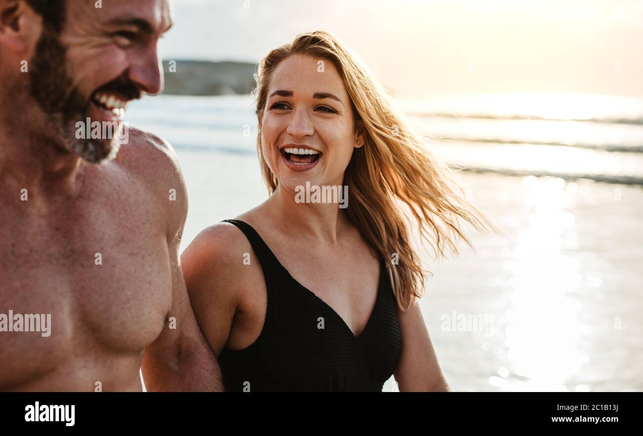 Lächelnder Mann und Frau, die zusammen am Strand entlang gehen. Pärchen genießen ein Sommerwochenende am Strand. Stockfoto