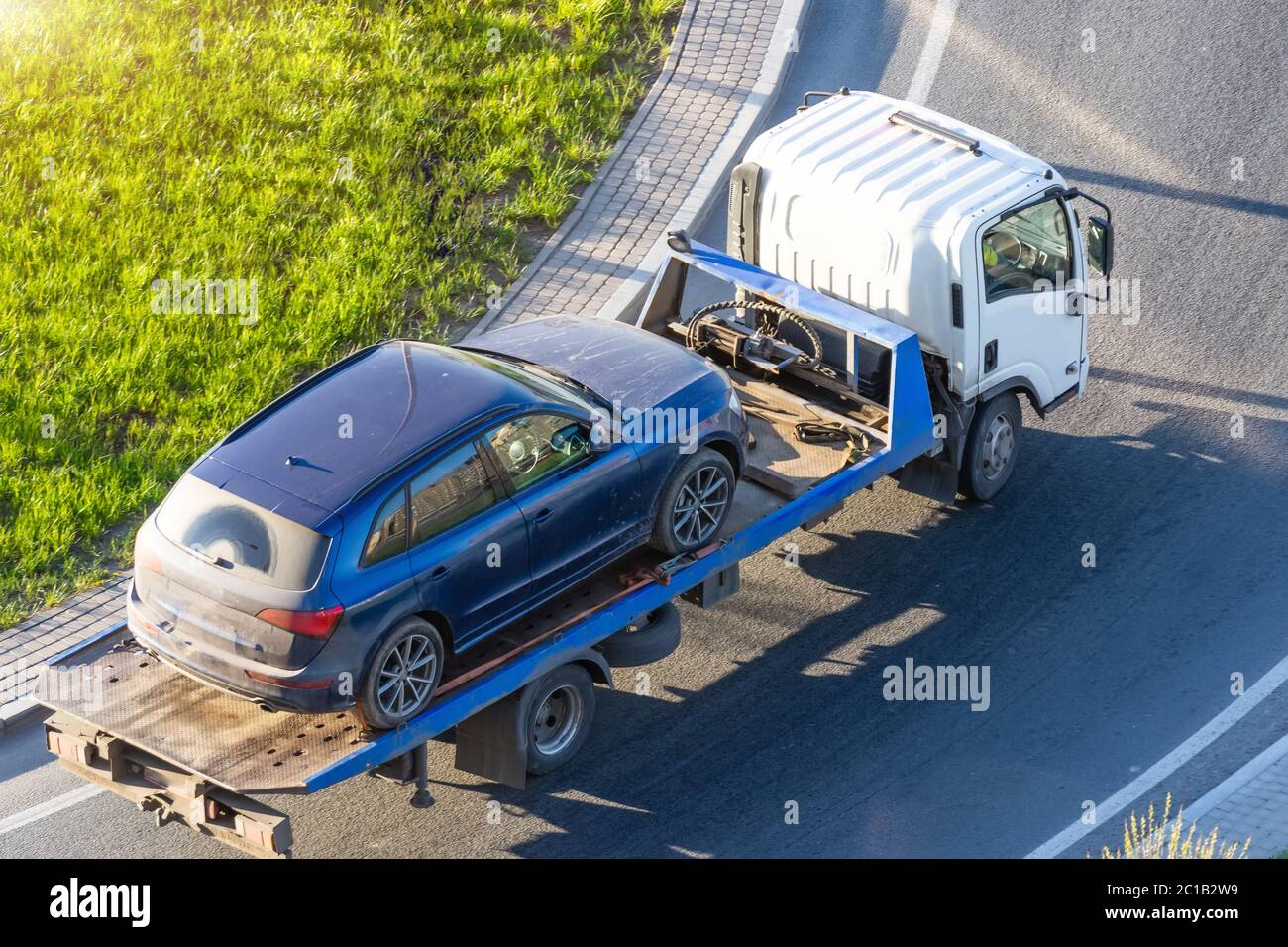 Die Evakuierung von Personenkraftwagen für illegale Parkplätze, die auf einen Evakuierungswagen beladen sind, fährt entlang der Straße und biegt auf die Autobahn ab, Luftaufnahme von oben Stockfoto