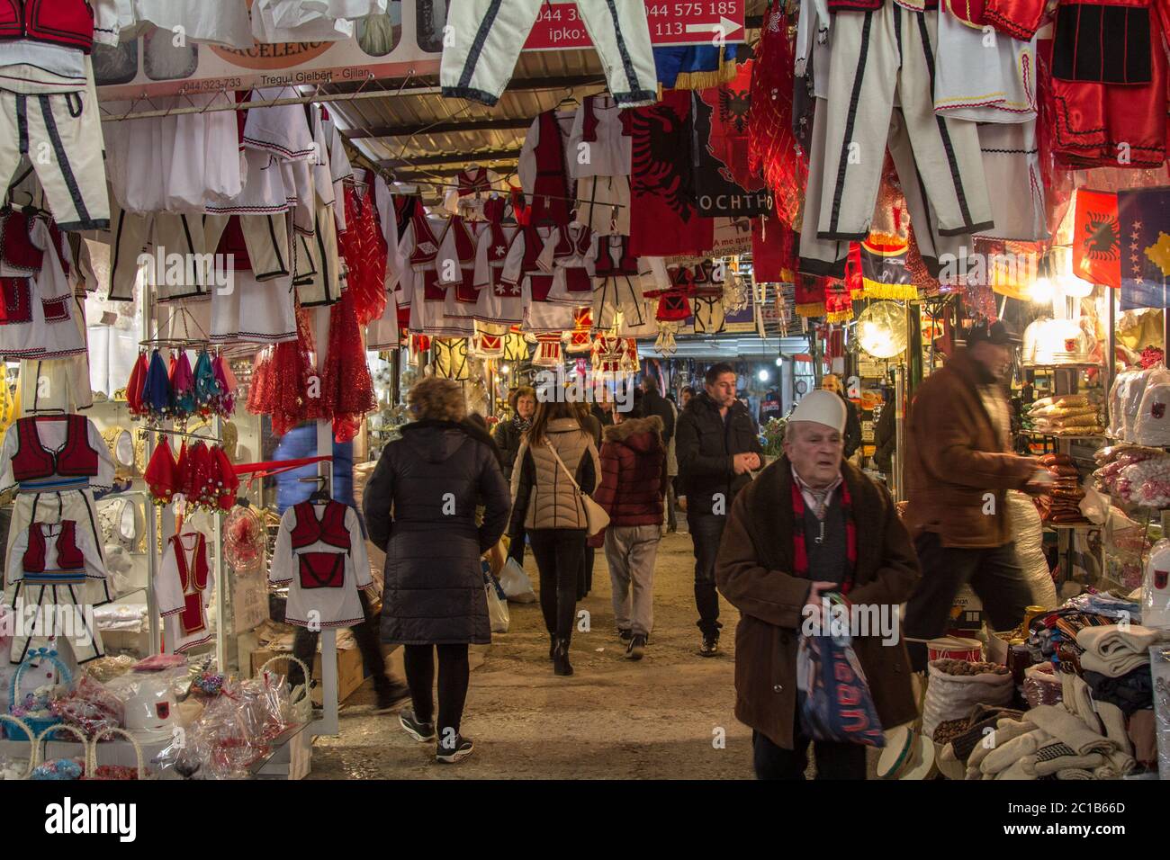 GNJILANE, GJILAN - KOSOVO - 2. JANUAR 2016: Stand auf dem Gjilan Bazar Markt mit albanischen Flaggen und anderen nationalen traditionellen Cosutmes und Kleidern Stockfoto