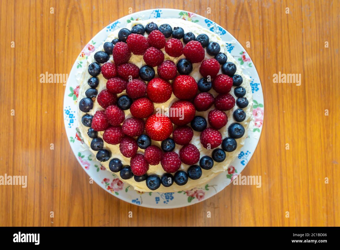 Ein Kuchen mit Buttereier und Sommerfrüchten wie Erdbeeren, Himbeeren und Heidelbeeren. Stockfoto