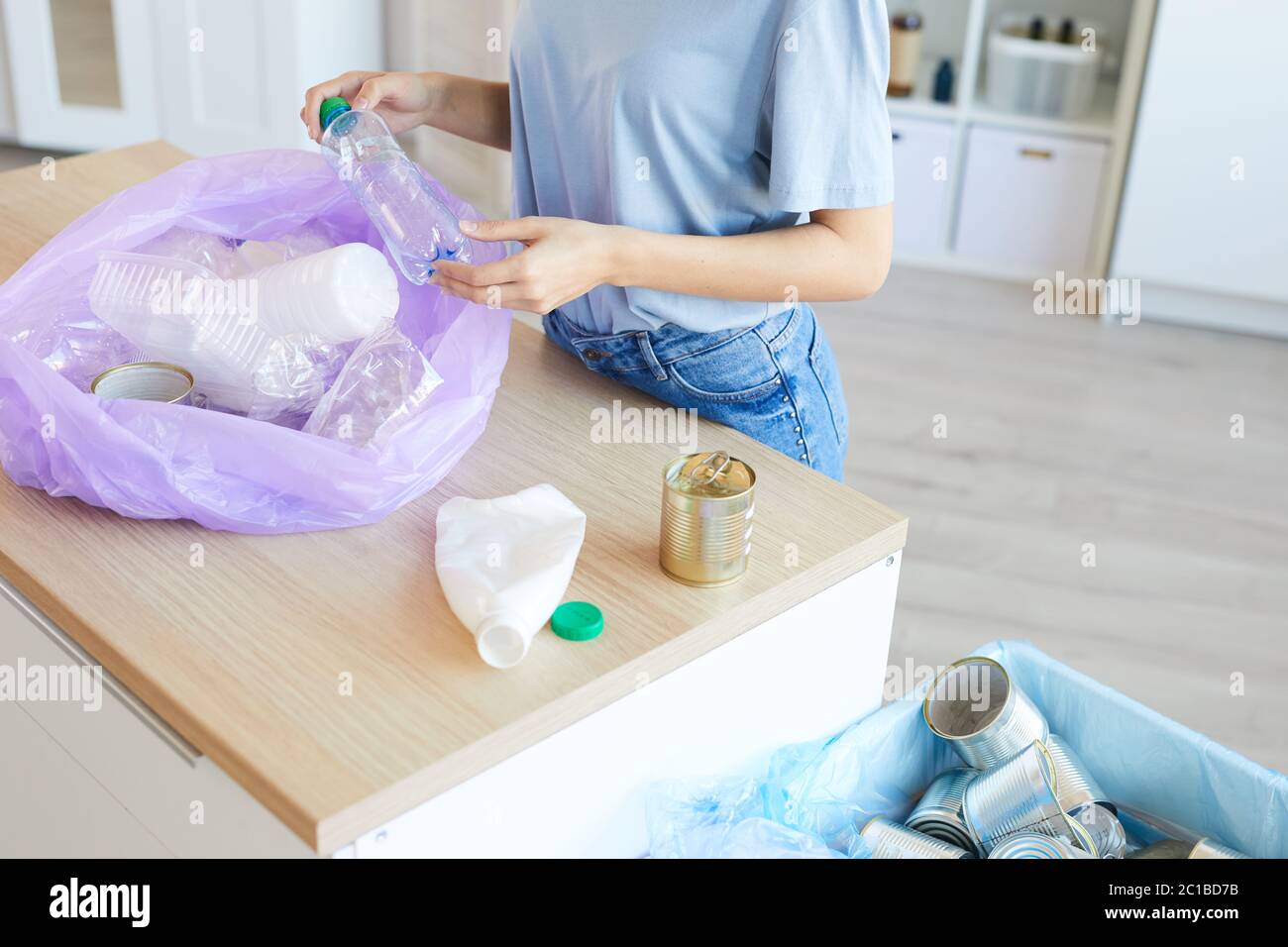 Nahaufnahme einer Frau, die am Tisch steht und Müll in die verschiedenen Pakete zu Hause sortiert Stockfoto