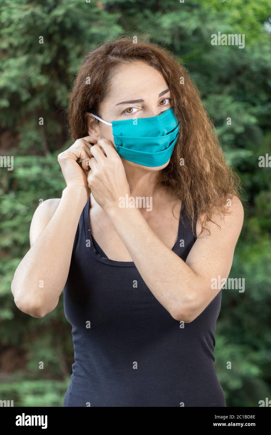 Eine fraue Frau im Sportswear-Stil, die in einer Sommer-Kamera eine Schutzmaske aufsetzt. Stockfoto