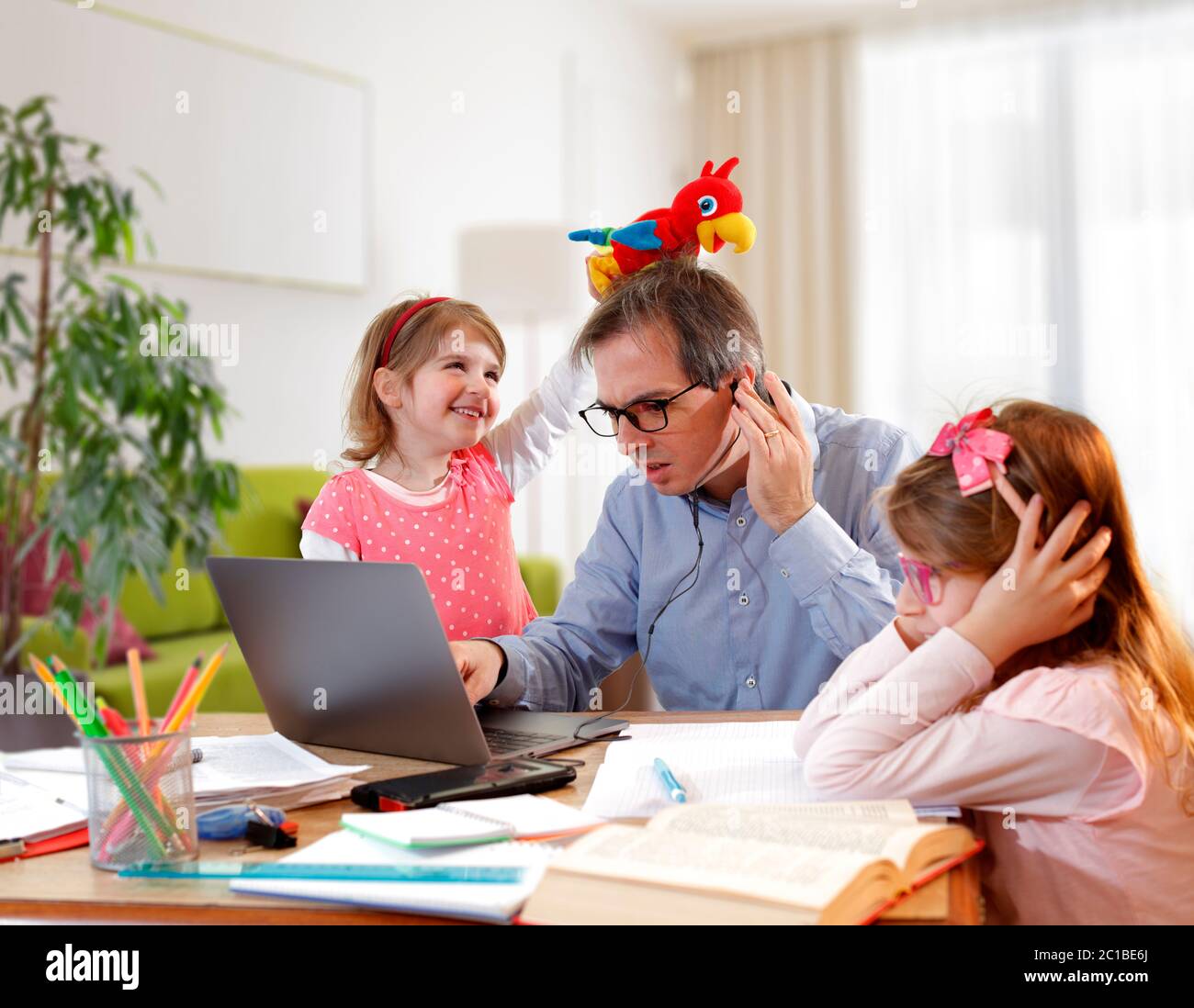 Caos - Vater und Schulmädchen arbeiten zu Hause - Telearbeit und E-Learning Stockfoto
