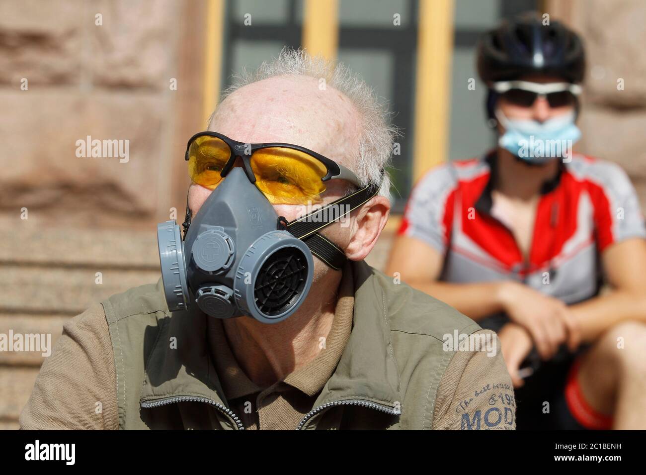 Ein Radfahrer schaut während des Protestes mit einer Gesichtsmaske auf, um die Prophylaxe zu erhalten.Radfahrer nehmen an der Einfahrdemonstration in der Nähe des Rathauses Teil, die den Bau von Fahrradwegen und die Verschärfung der Verkehrsregeln in Kiew, Ukraine, fordert. Stockfoto