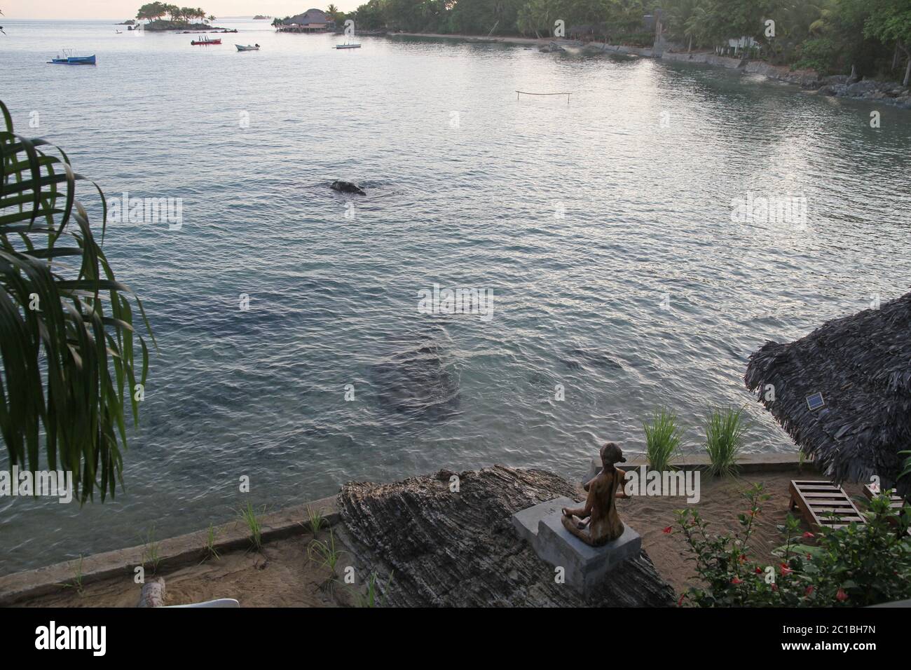 Holzstatue mit Blick auf Strand bei Flut am Strand, 293 auf Komba Guest House, Ampangorinana Village Nosy Komba Island, Madagaskar. Stockfoto