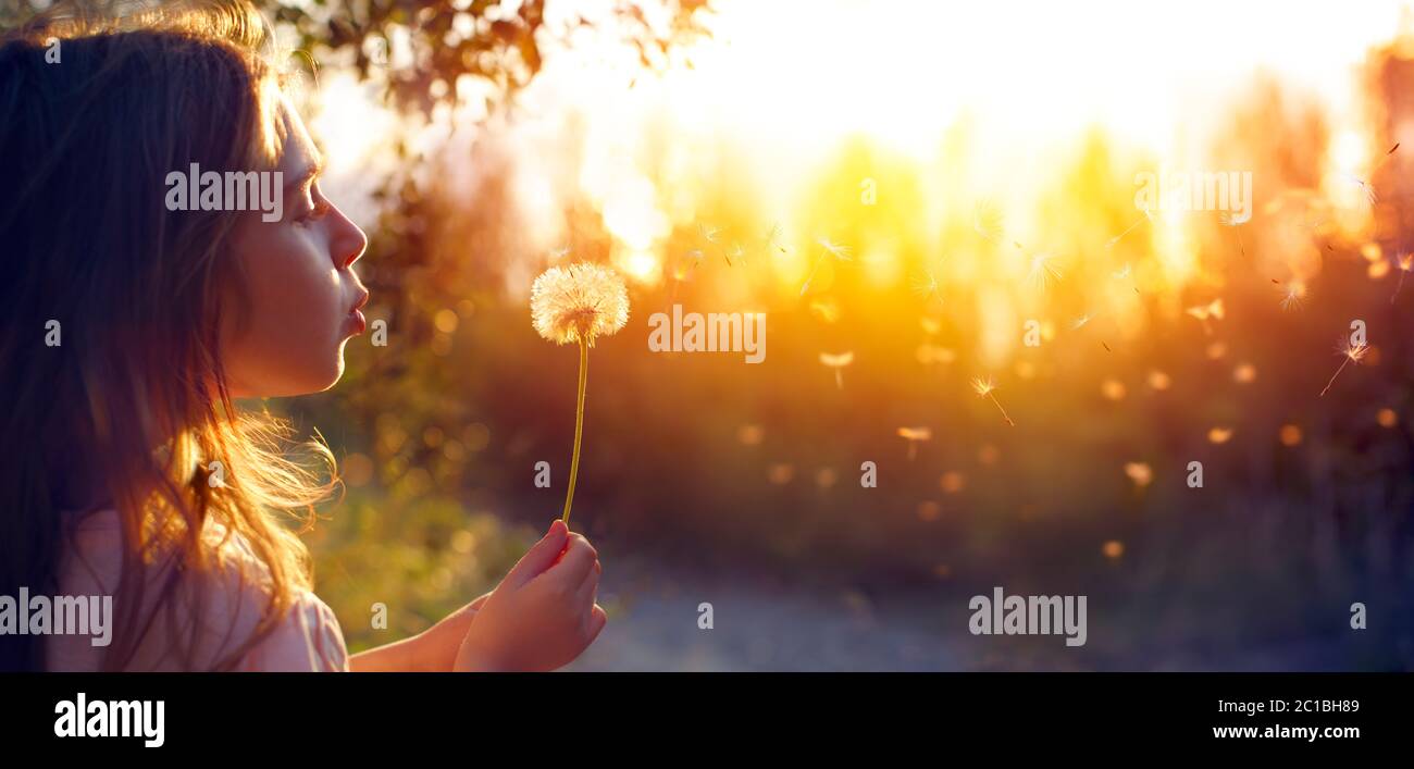 Little Girl Blowing Löwenzahn Blume Bei Sonnenuntergang - Unfokussed Hintergrund Stockfoto