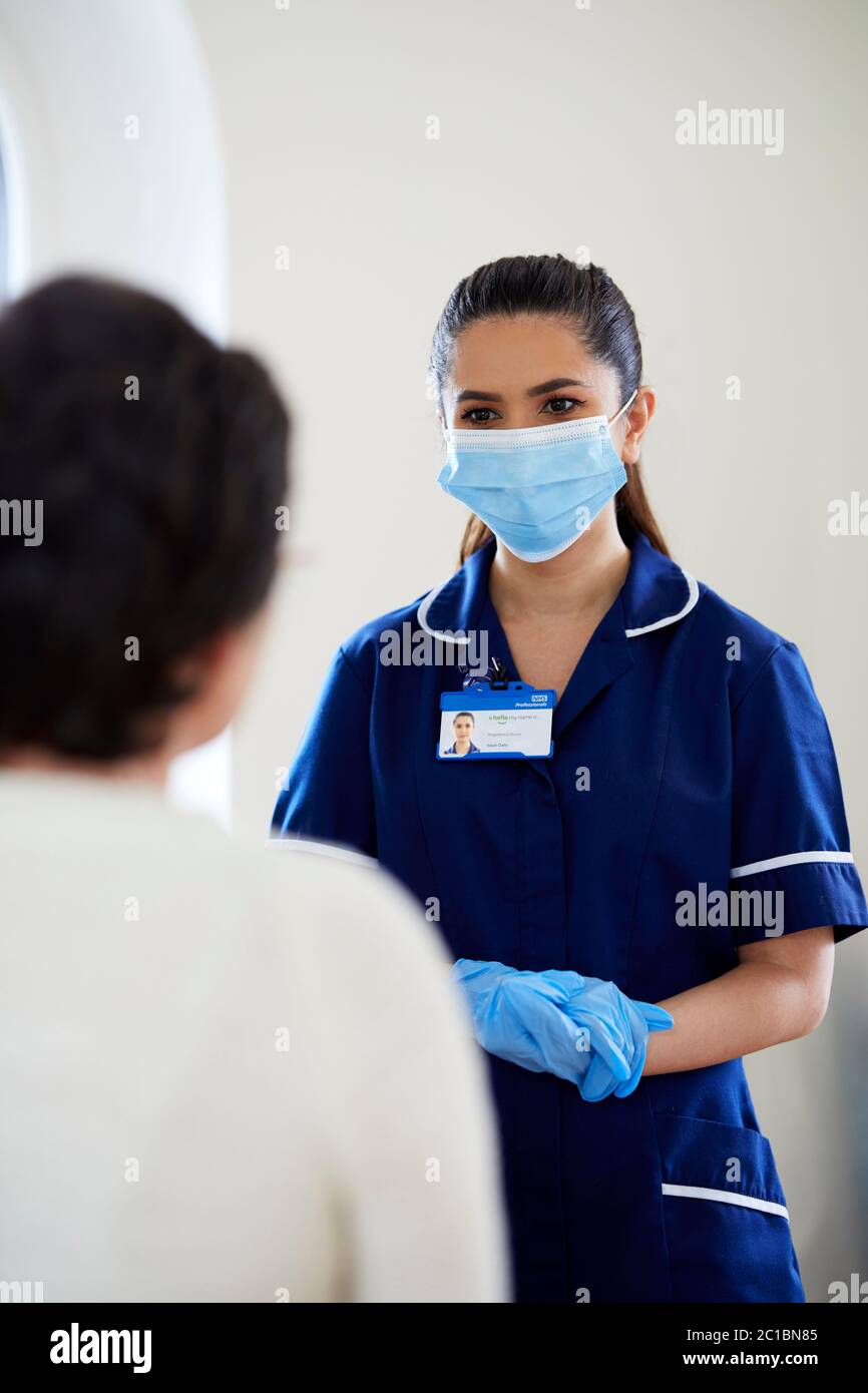Krankenschwester mit PSA-Maske und Handschuhen, die mit dem Patienten sprechen Stockfoto