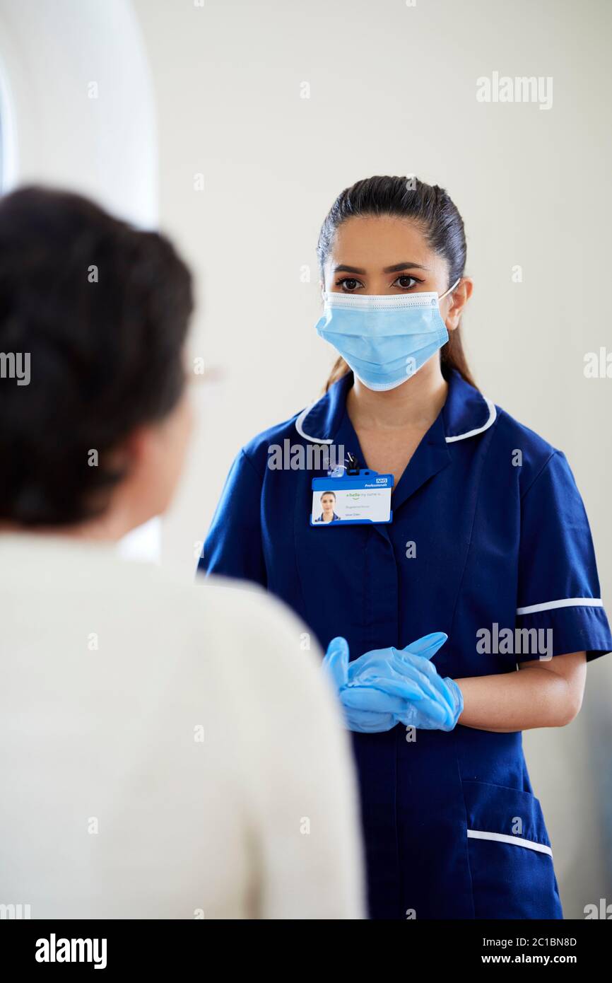 Krankenschwester mit PSA-Maske und Handschuhen, die mit dem Patienten sprechen Stockfoto