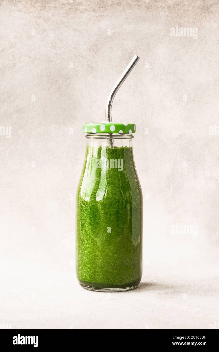 Grüner Smoothie mit Spinat in kleiner Flasche mit Metallstroh. Platz für Text kopieren. Gesundes Lifestyle-Konzept Stockfoto